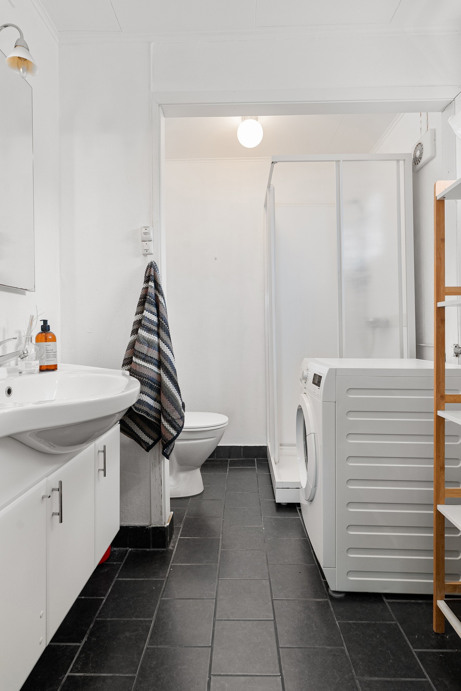 Bad/wc/vaskerom i utleiedel med fliser på gulv, gulvvarme, wc, lys baderomsinnredning og dusjkabinett. Galleribilde