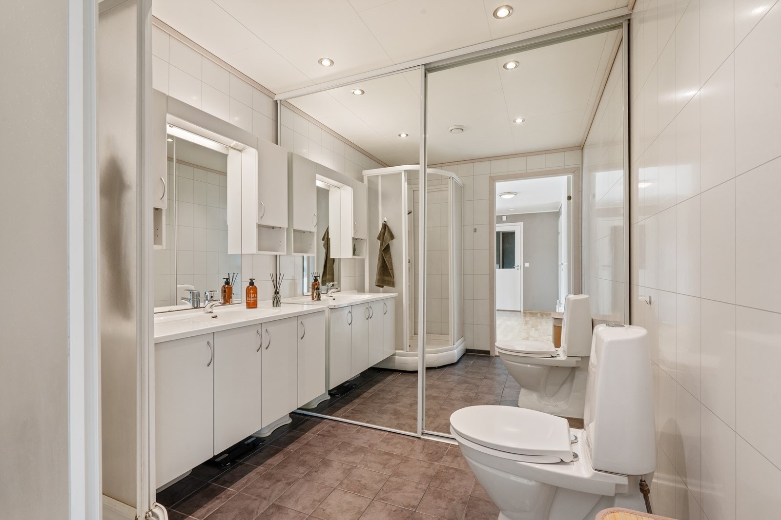 Badet har flislagt gulv med gulvvarme. Opplegg for vaskemaskin bak skyvedører med speilfront. Galleribilde