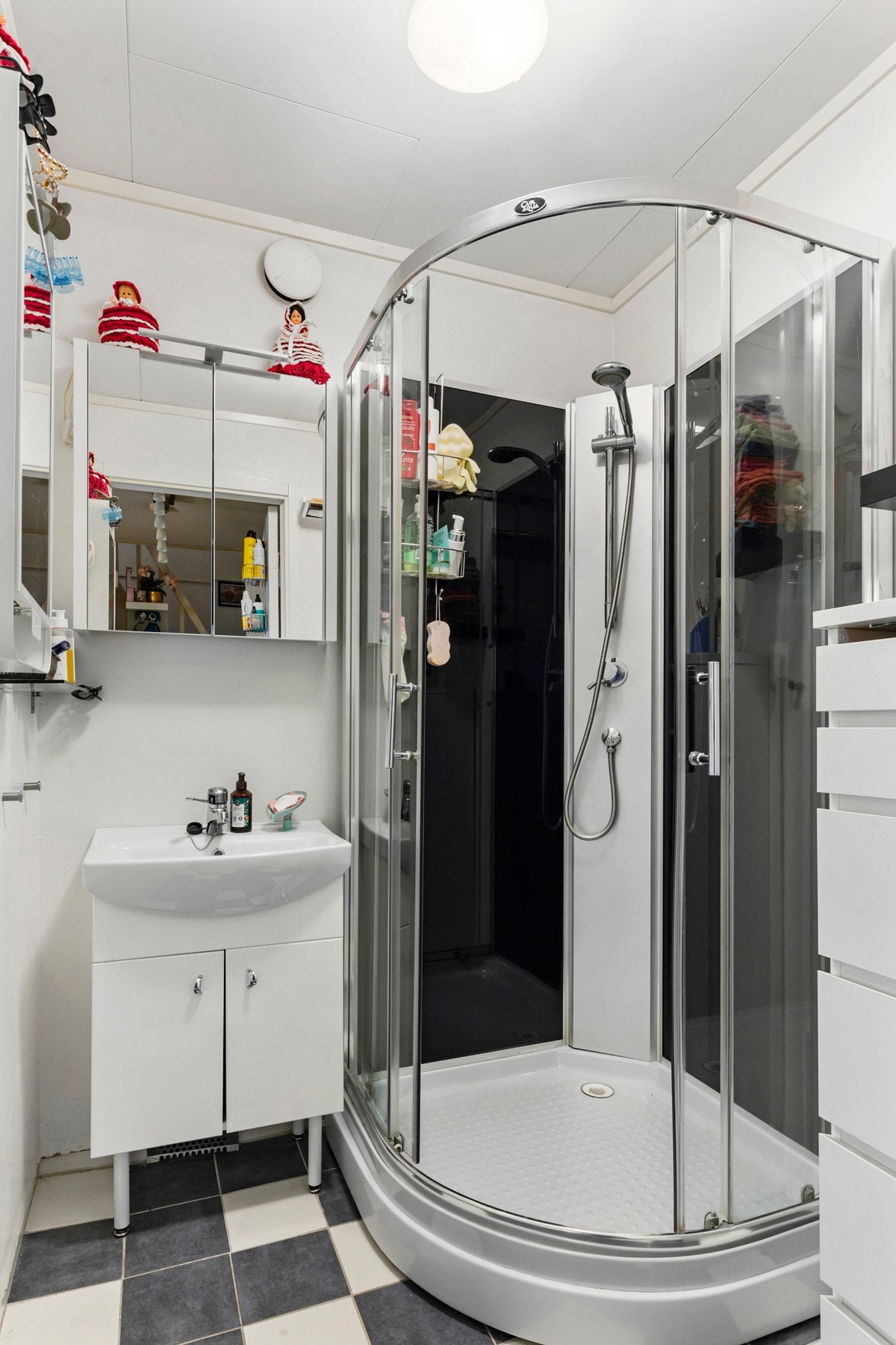 Baderom med flis på gulv og våtromstapet på vegger. Badet er utstyrt med dusjkabinett, reflektorovn, servantskap og naturlig avtrekk. Galleribilde