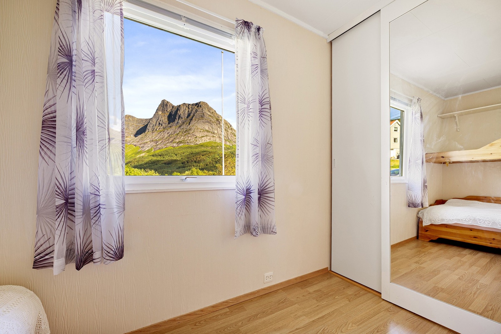 Fjelltoppen rammes inn av vinduet i dette soverommet. Speildør på garderoben og god plassering i boligen Galleribilde