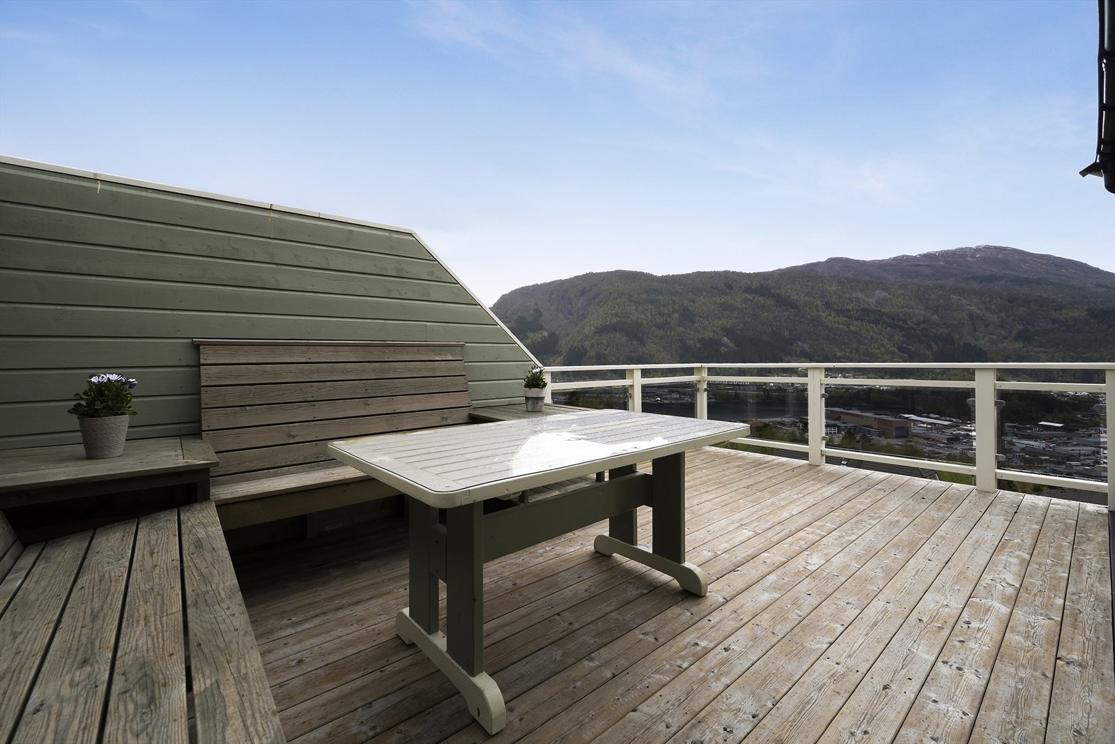 Fra kjøkkenet er det utgang via skyvedør til veranda med terrassebord, rekkverk i trevirke med glassfronter og malte levegger i trevirke. Galleribilde