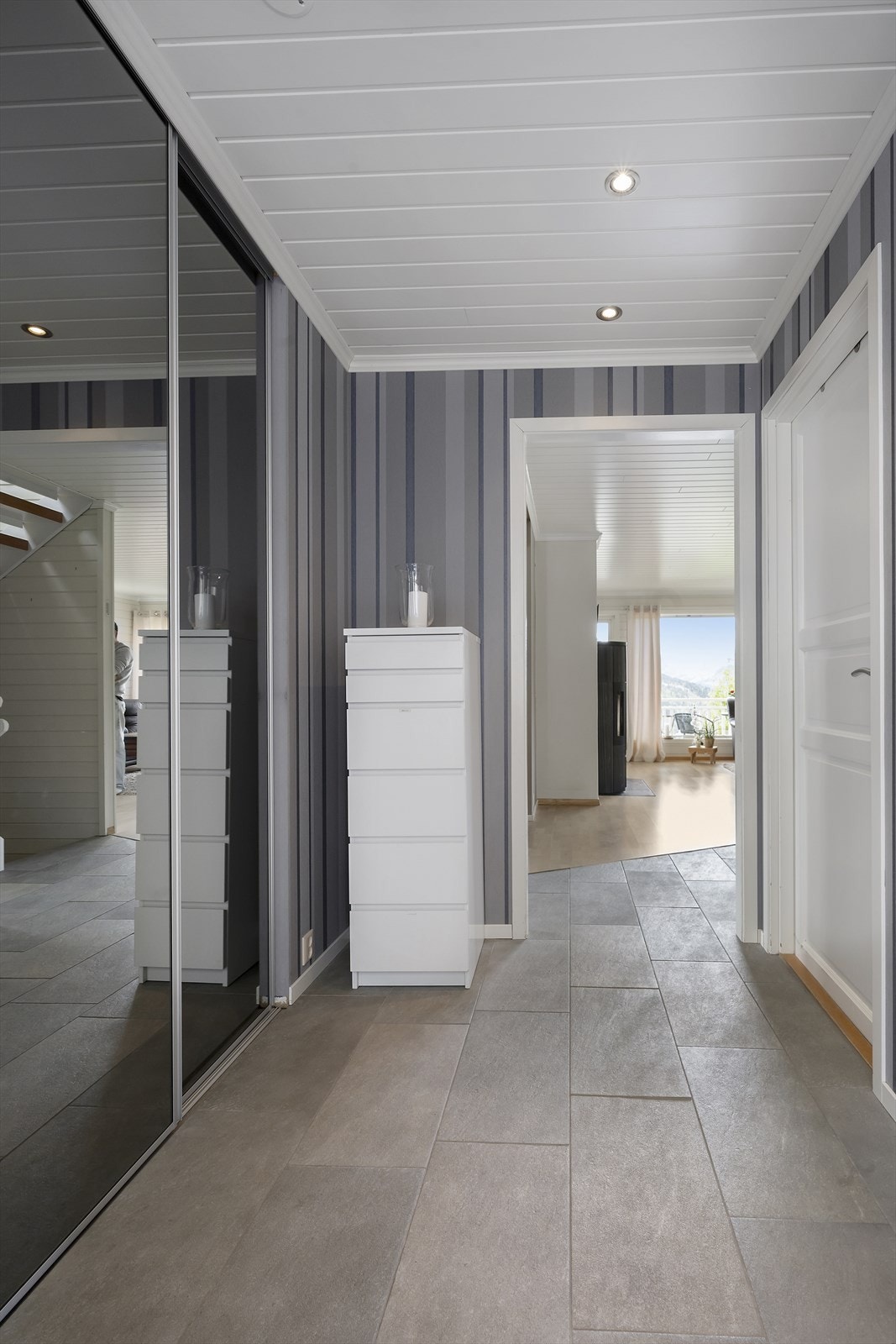 Trapperom med flislagt gulv og stor praktisk skyvedørsgarderobe. Galleribilde