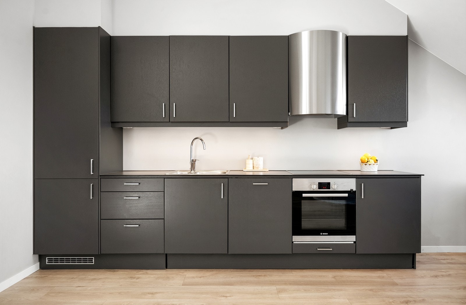Stilfullt kjøkken fra Sigdal av nyere dato med slimline laminat benkeplate, integrerte hvitevarer og moderne avtrekkshette fra RørosHetta (mekanisk avtrekk) Galleribilde