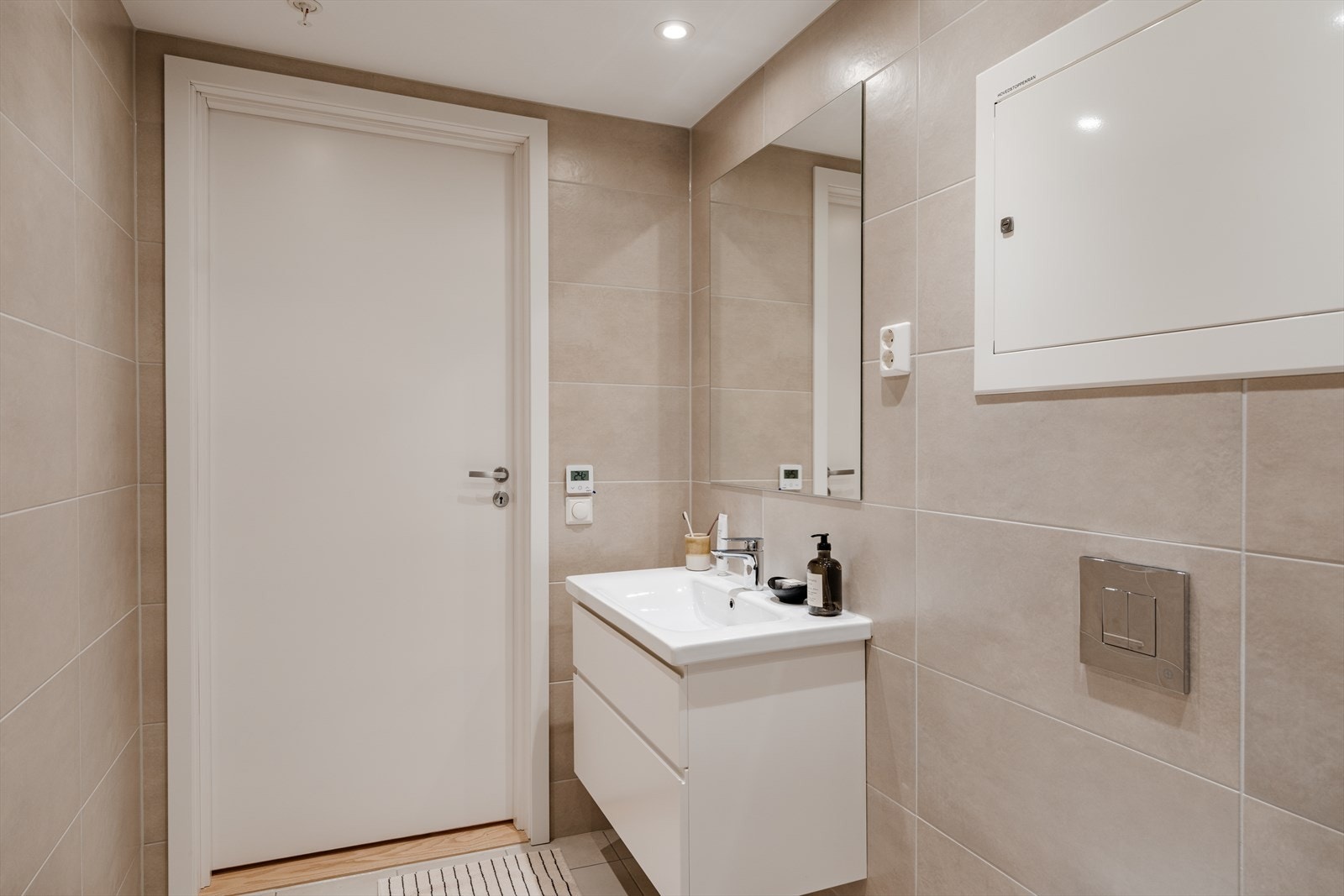Badet er innredet med servantskap med ett-greps blandebatteri, veggspeil, vegghengt toalett med innebygget sisterne, avskjermet dusjhjørne Galleribilde