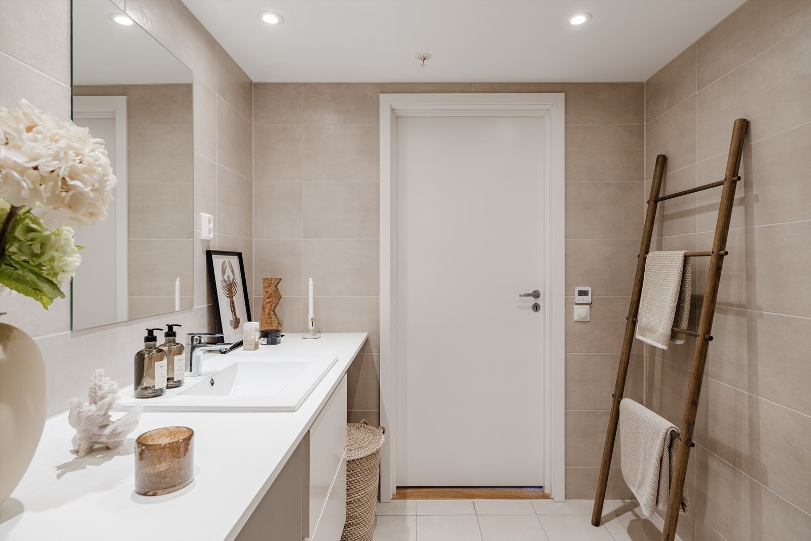 Badet er innredet med servantskap med ett-greps blandebatteri, veggspeil, vegghengt toalett med innebygget sisterne, avskjermet dusjhjørne med glass, blandebatteri og dusjgarnityr. Galleribilde