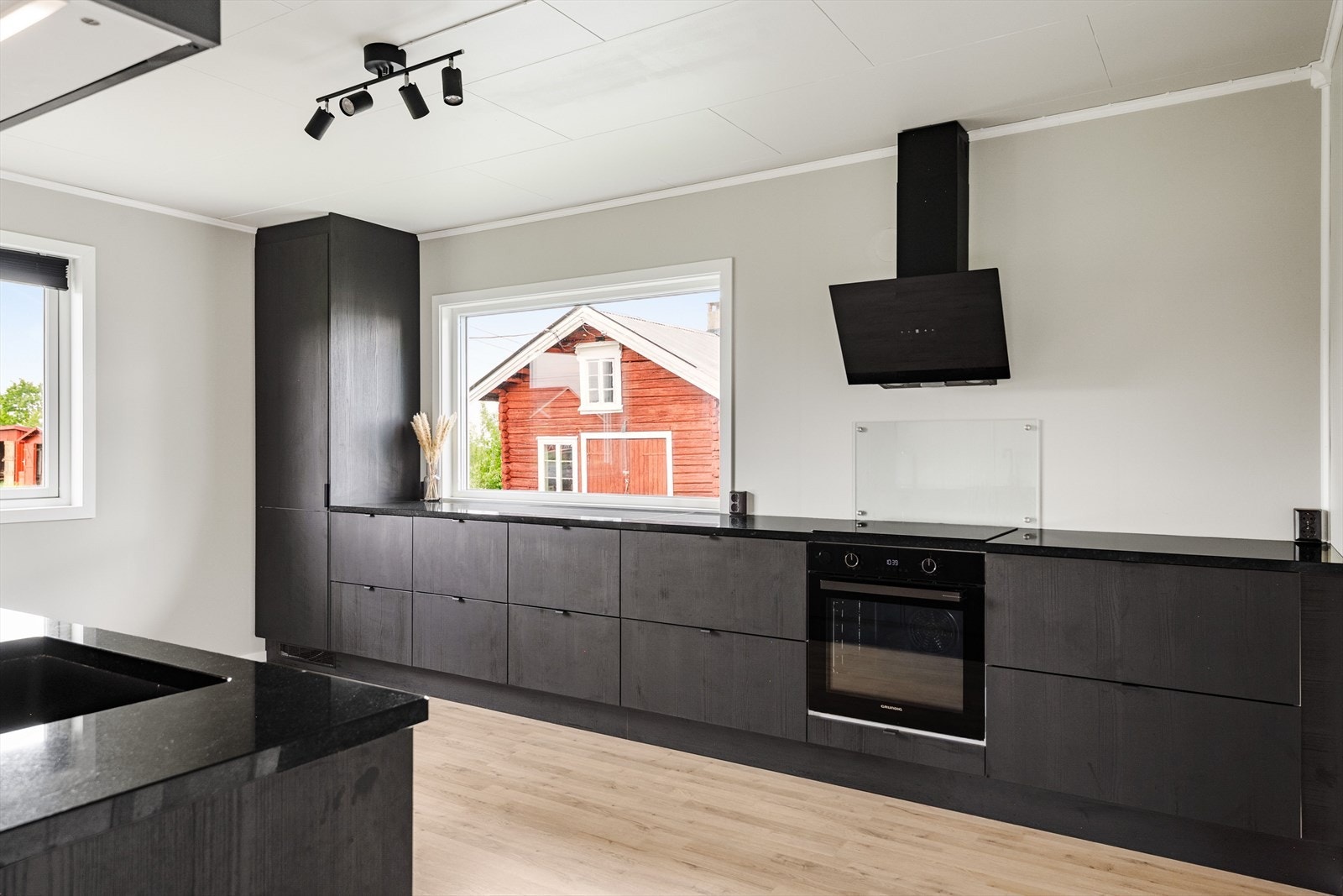 Pent kjøkken fra 2024 med glatte fronter og beneplate av stein. Galleribilde