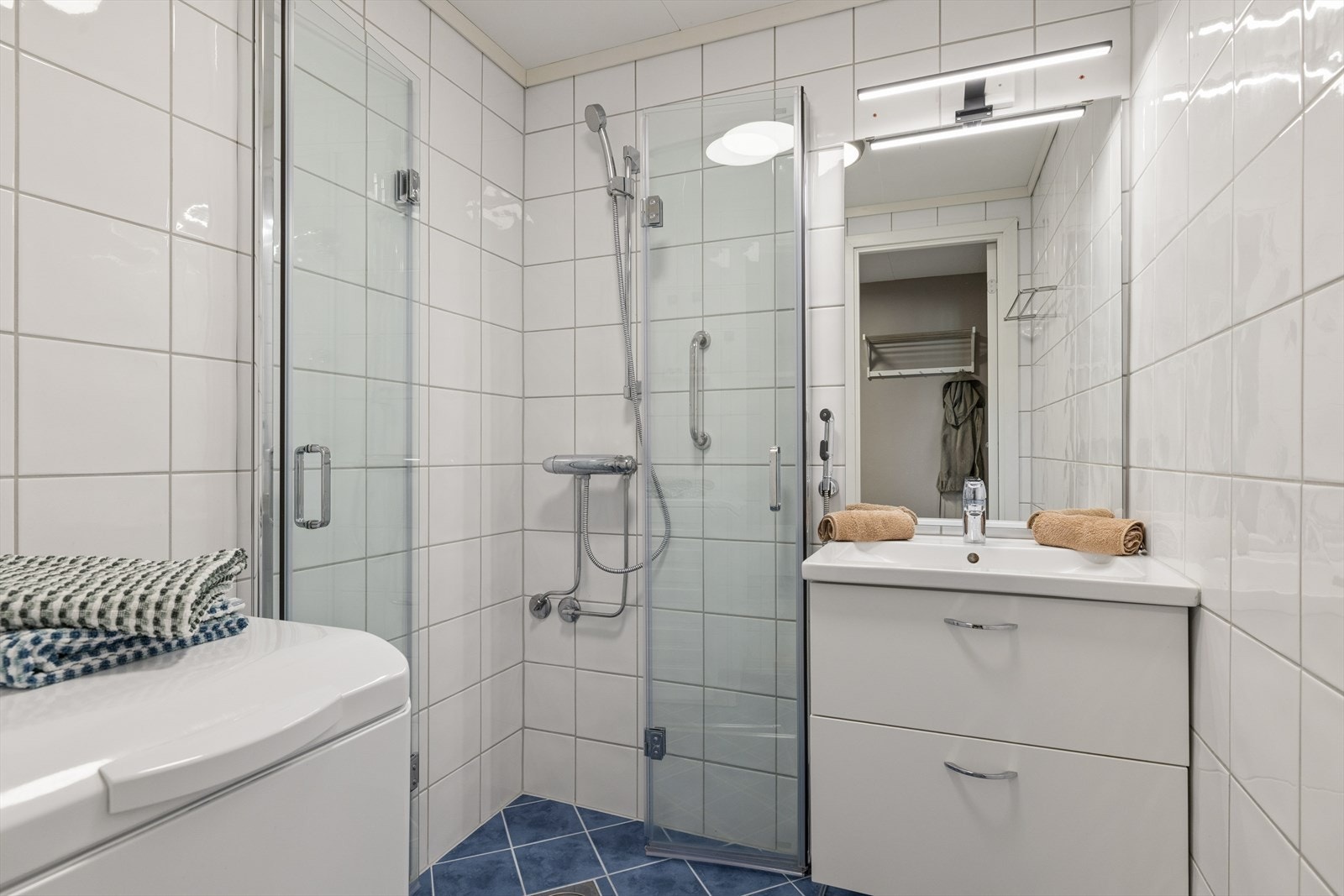 Badet er funksjonelt innredet med hjørnedusj, servant og opplegg for vaskemaskin/tørketrommel. Galleribilde