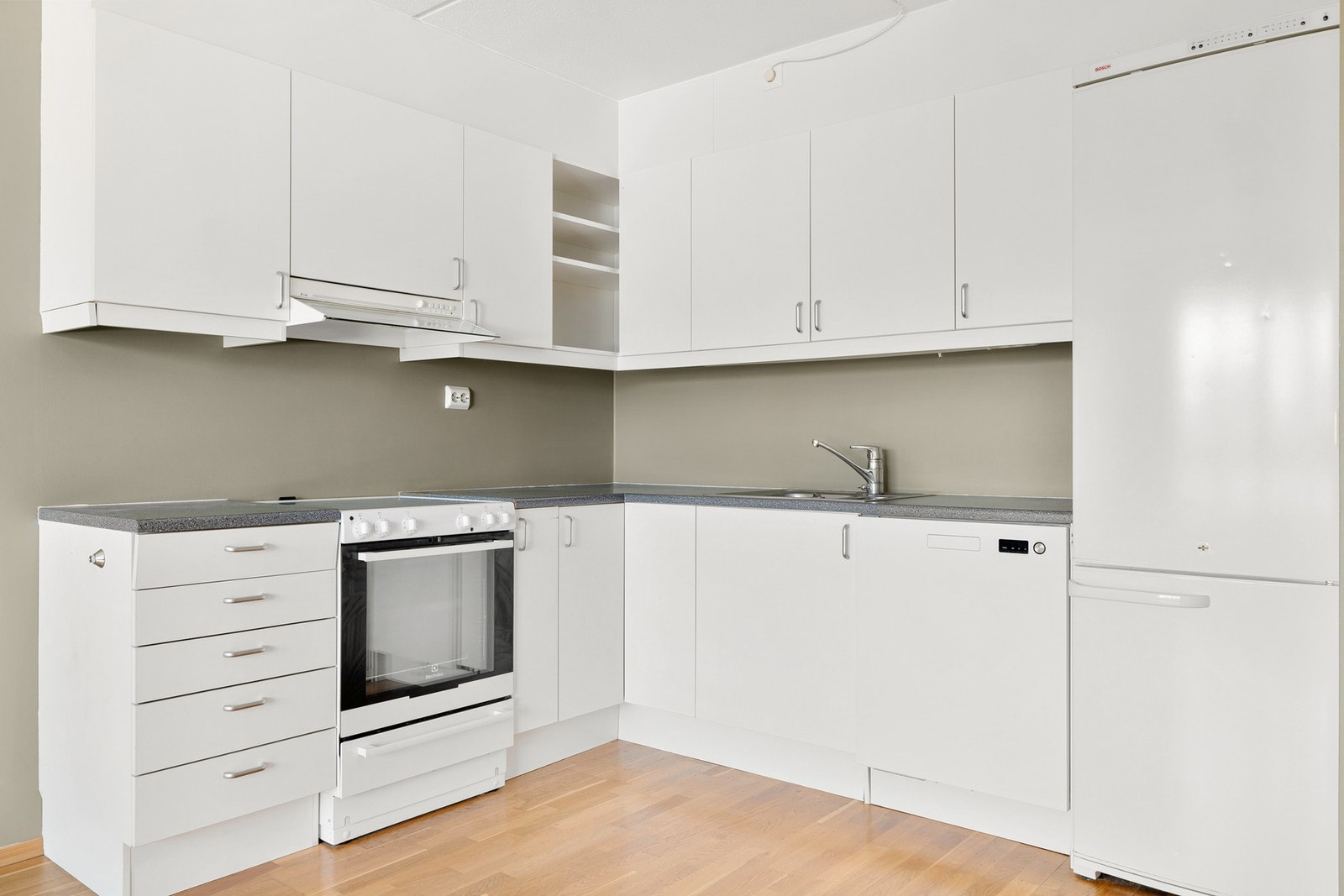 Funksjonelt kjøkken fra byggeår. Innredningen har glatte fronter i hvit utførelse kombinert med benkeplate av laminat. Galleribilde