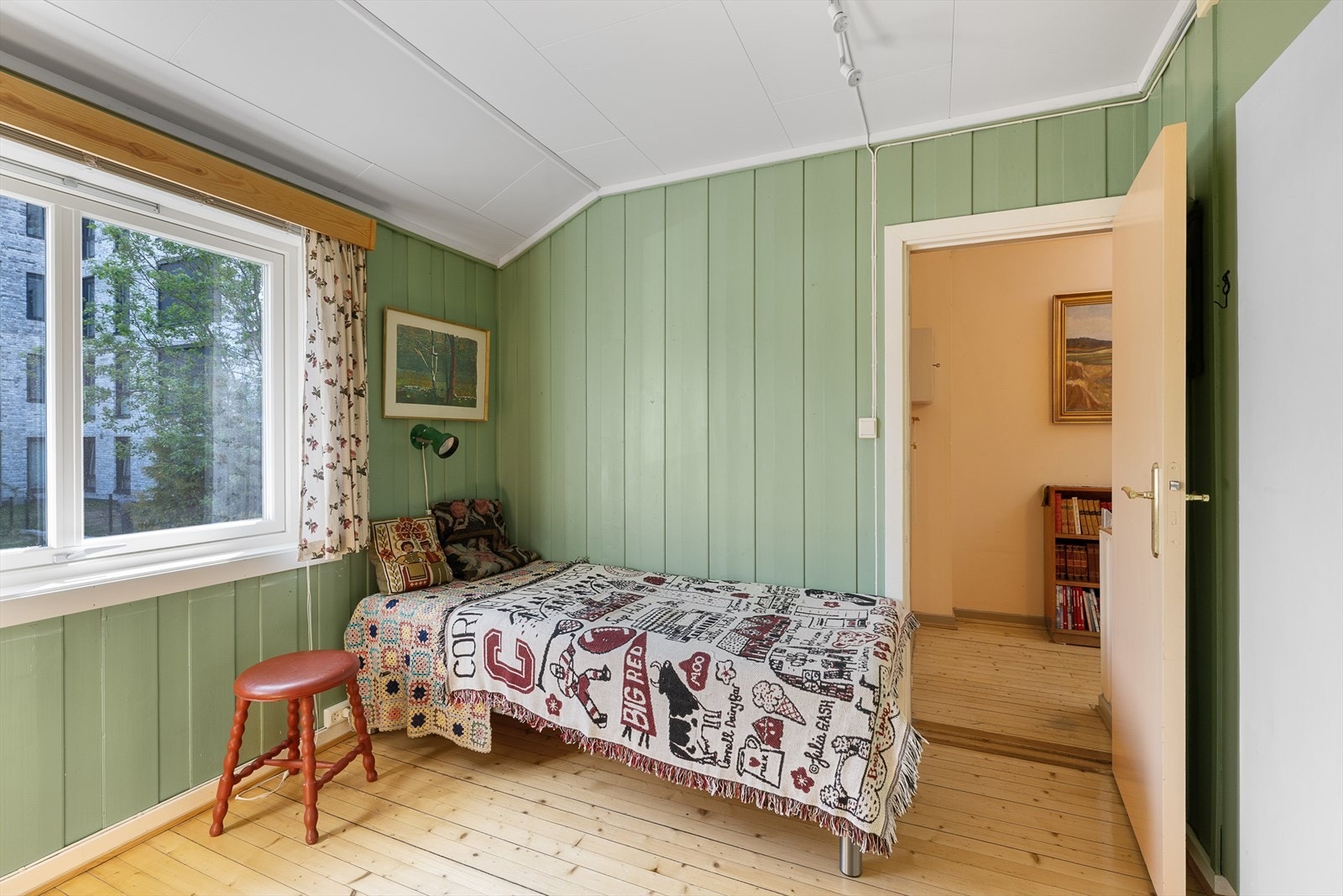 Rommet har tregulv og panel på veggene, og plass til en liten arbeidsplass ved vinduet. Galleribilde