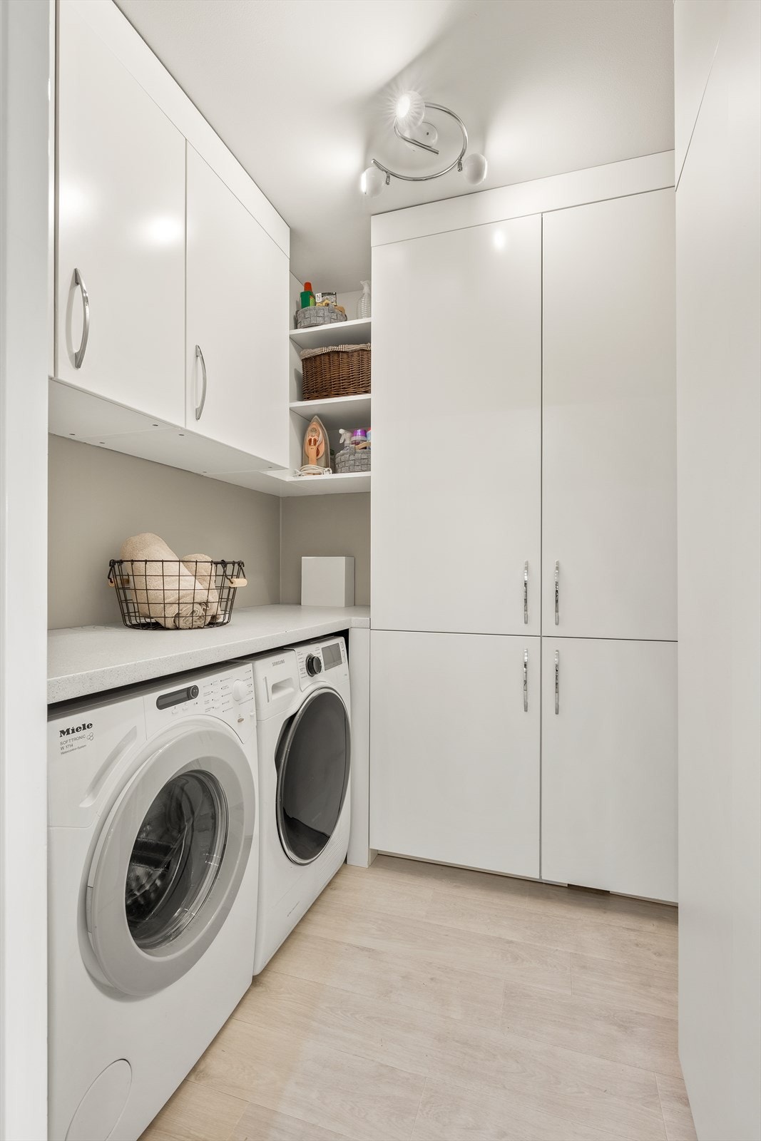 Praktisk vaskerom med belegg på gulv, malte vegger og malt himling. Opplegg for vaskemaskin og tørketrommel. Innredningen er spesialtilpasset og utført av møbelsnekker for optimal utnyttelse av plassen. Galleribilde