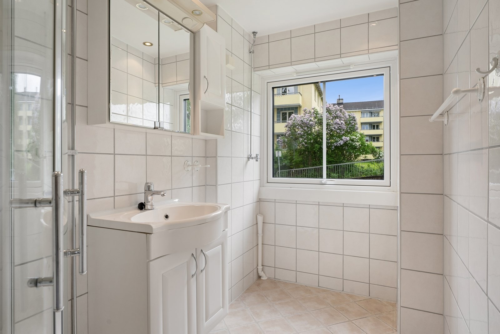 Badet er et lyst rom med lyse fliser på vegger og gulv. Galleribilde