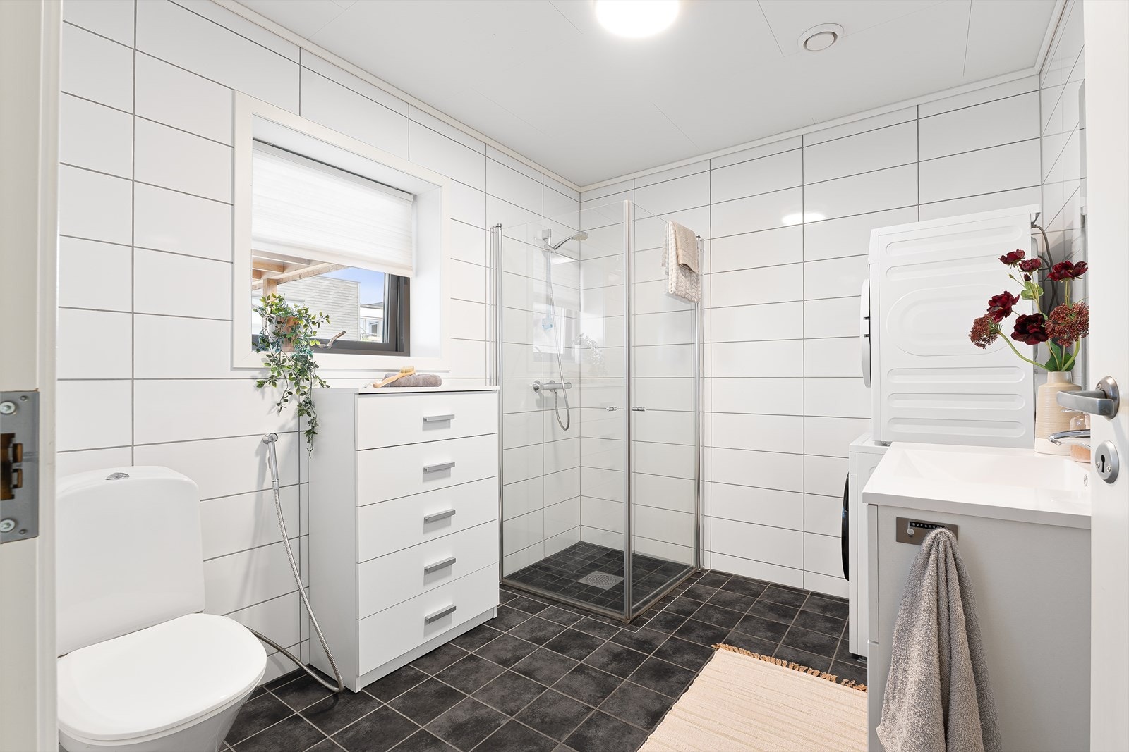 Flott bad på 6,9m² med behagelig varme i gulv. Innredet med servant, dusj med glassdører, klosett, opplegg for vaskemaskin og mekanisk avtrekk. Galleribilde