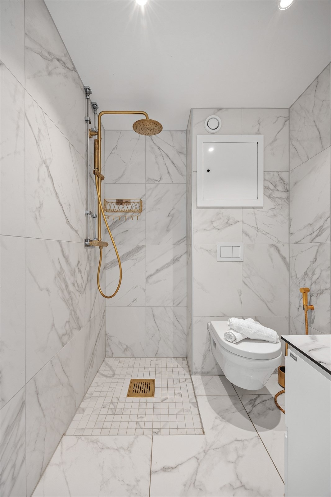 Badet er utstyrt med innredning med skuffer, servant, speil, toalett og dusj på gulv. Det er mekanisk avtrekk på badet. Galleribilde