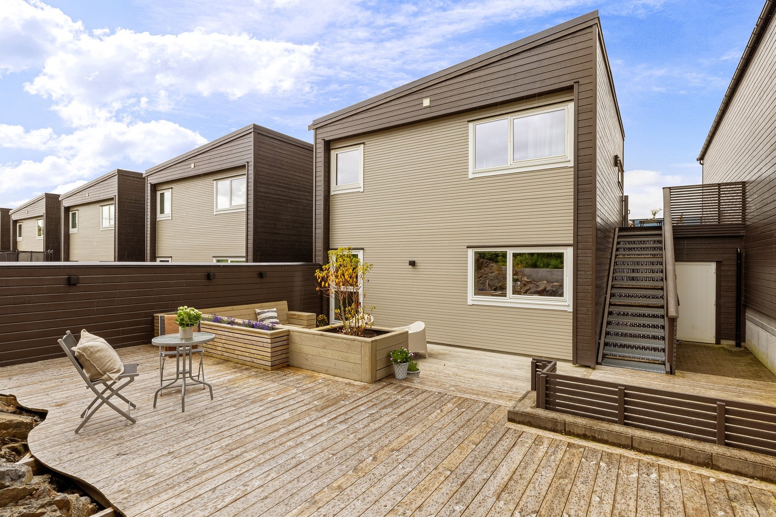 Terrassen på bakkeplan og balkongen i hovedetasjen er elegant knyttet sammen med utvendig trapp, noe som skaper et helhetlig og funksjonelt uteområde. Galleribilde