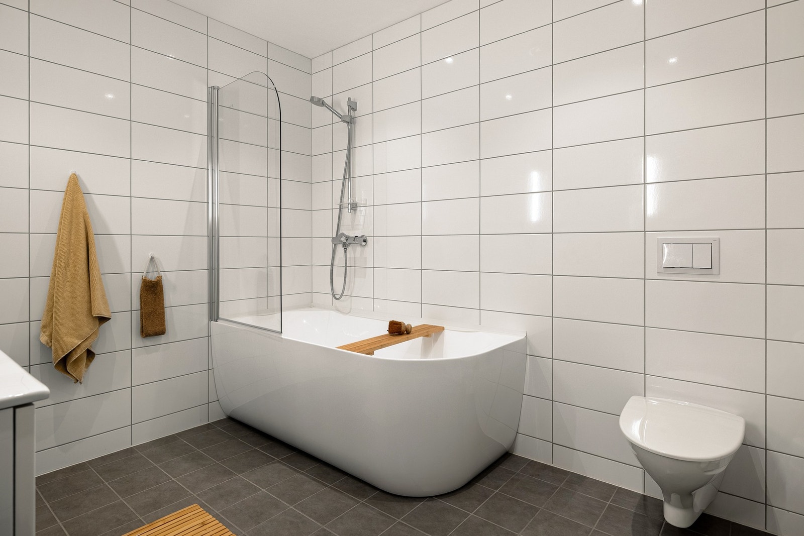 Badet er innredet med badekar, vegghengt toalett og skuffeinnredning med overliggende servant. Galleribilde