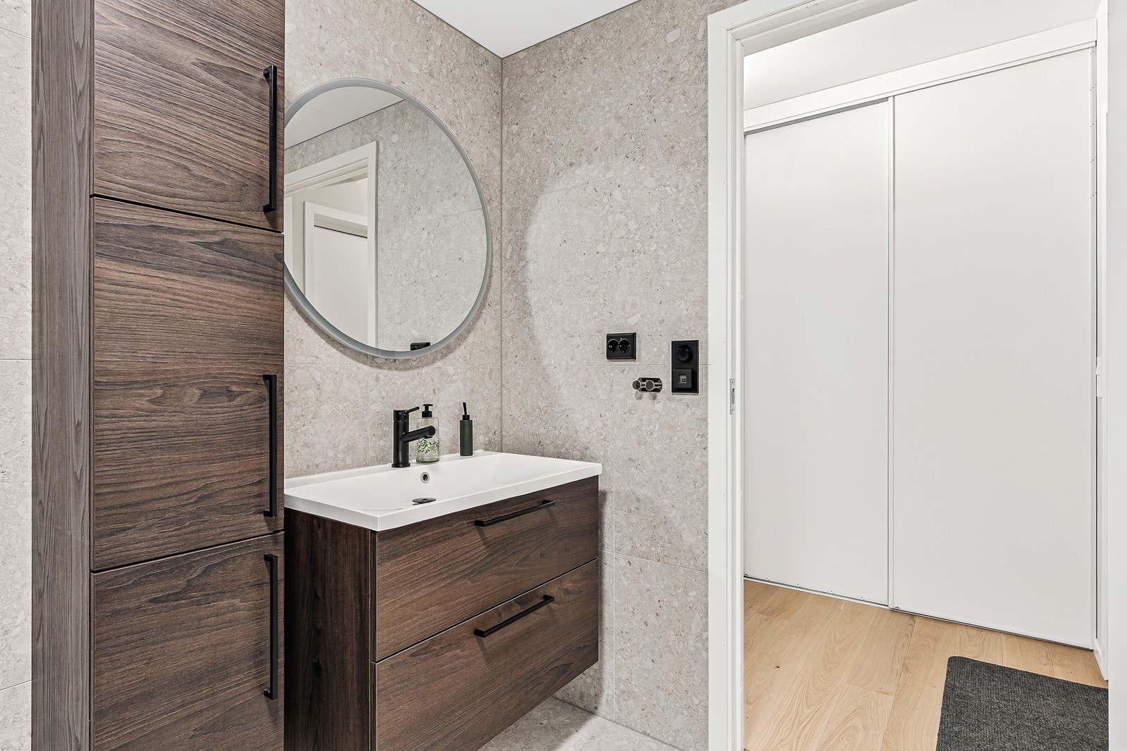 Badet er lekkert og helfliset, og innredet med servant med skuffer, høyskap, gulvstående toalett og dusjhjørne med glassvegger. Galleribilde