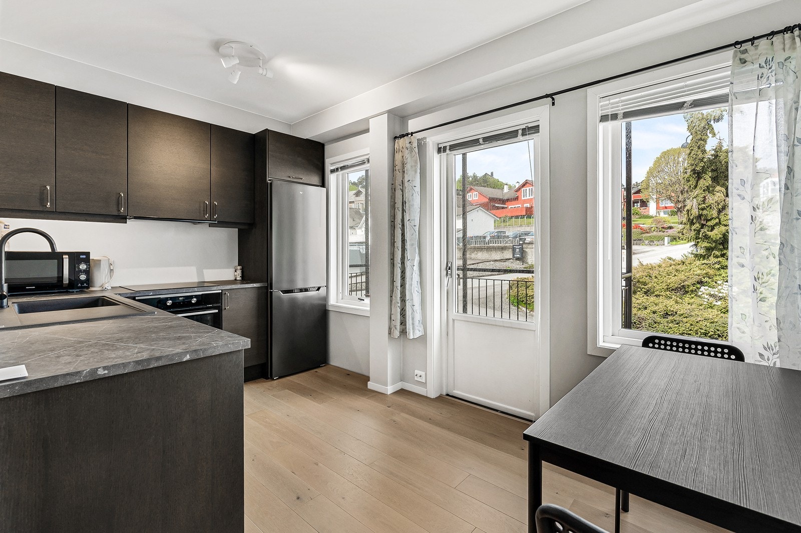 Kjøkkenet har en moderne og flott innredning med sorte fronter, laminat benkeplate og nedfelt vask i kompositt. Galleribilde