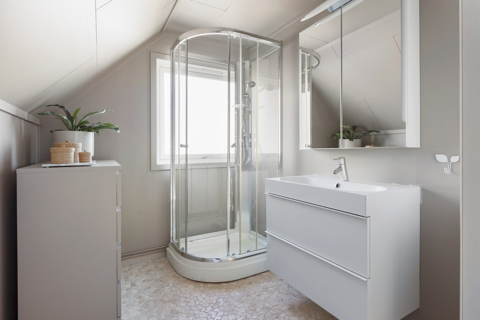 Badet er utstyrt med nyere vegghengt servantinnredning med skuffer og speilskap med lys. Galleribilde