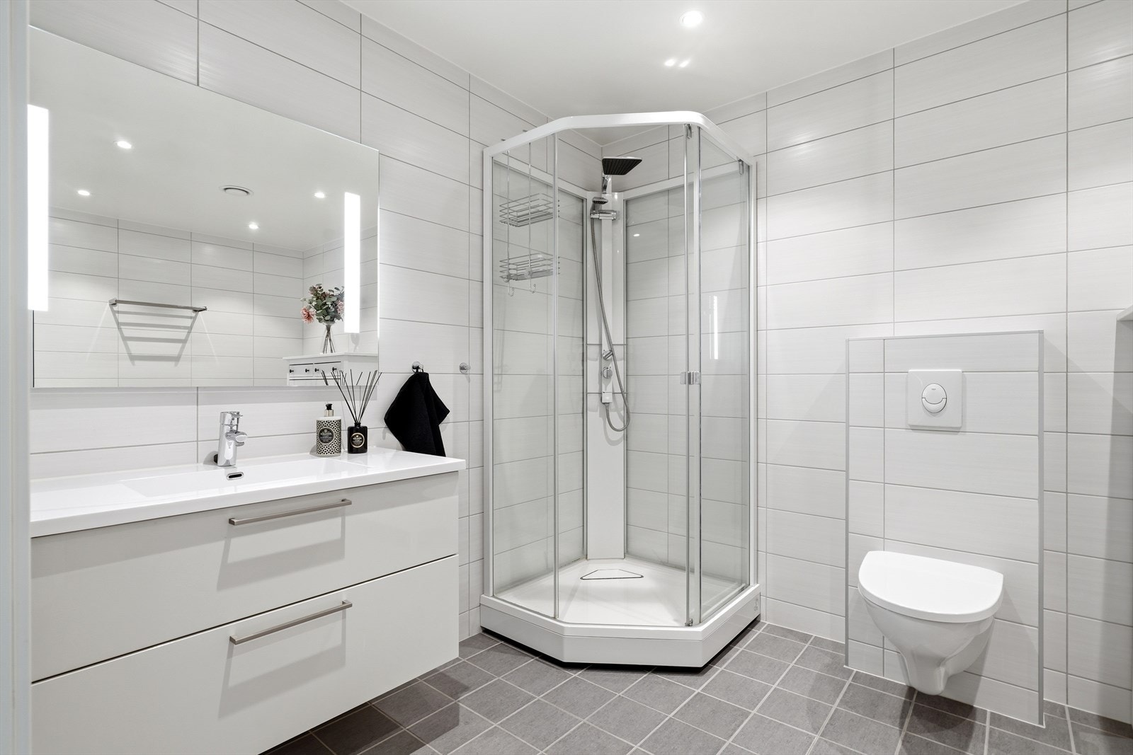 Badet er innredet med dusjkabinett, vegghengt toalett og servant med skuffeseksjon. Galleribilde