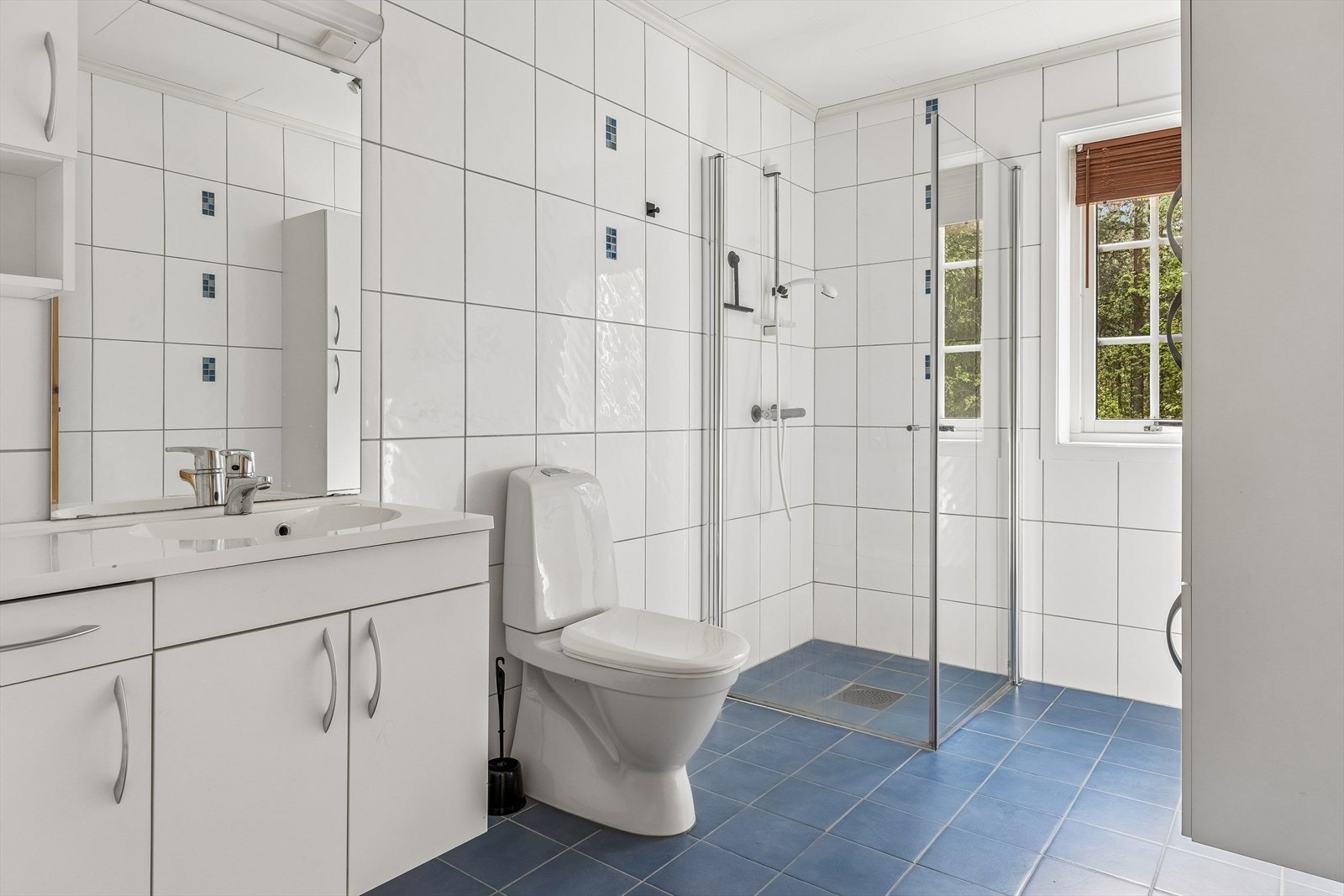 Badet i hovedetasjen er flislagt og har elektriske varmekabler i gulvet, dusjdører i glass og mekanisk baderomsvifte. Galleribilde