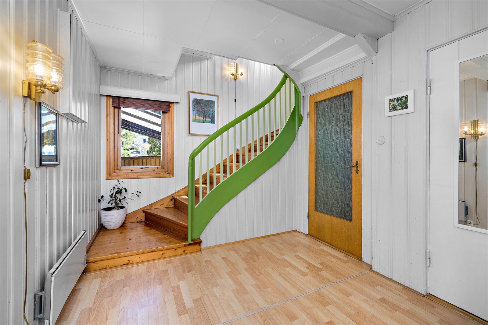 Hallen fungerer som et knutepunkt i boligen, med trapp i treverk som fører opp til andre etasje. Galleribilde