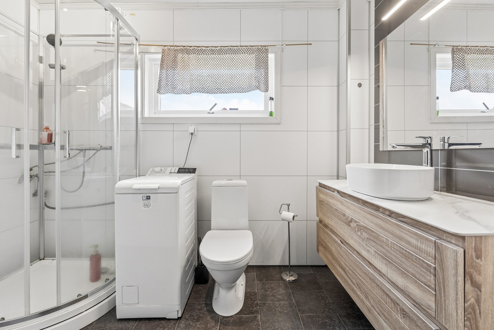 Rommet er utstyrt med dusjkabinett, toalett og elektrisk styrt vifte for ventilasjon. Galleribilde