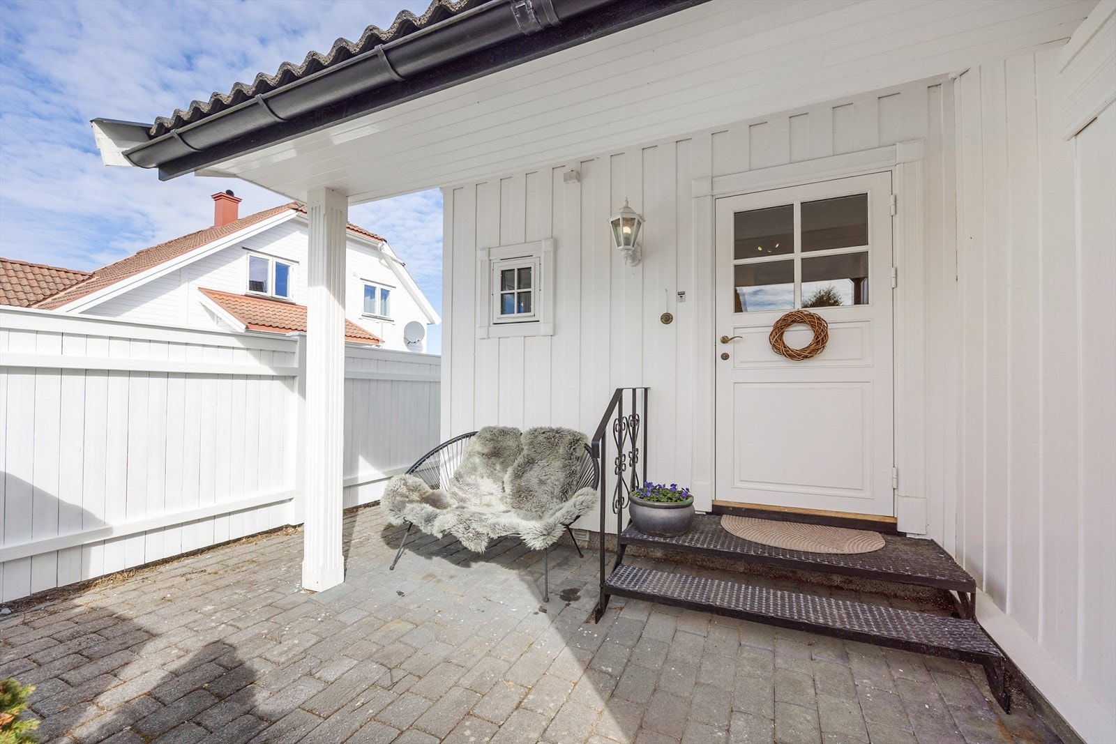 Hyggelig inngangsparti med belegningsstein og takoverbygg. Inngangspartiet ligger lunt og usjenert til, skjermet av levegger, med smijernstrapp. Galleribilde