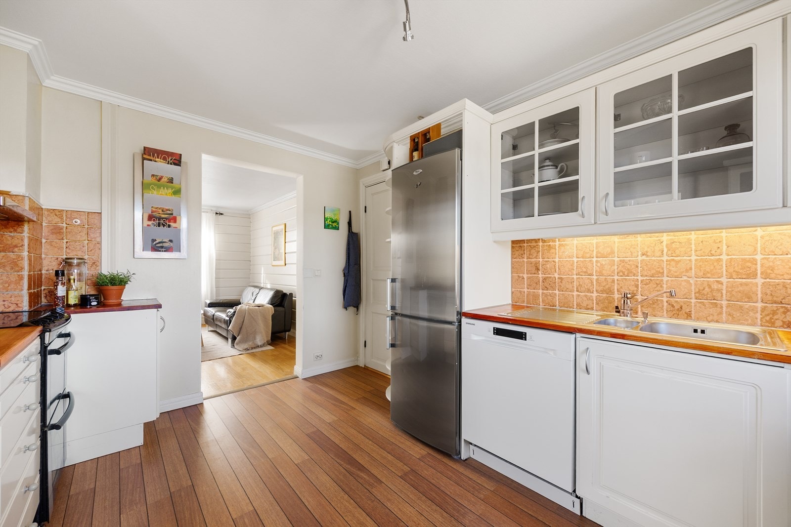 Flis på vegg over heltre benkeplate med gode arbeidsflater og nedfelt benkebeslag. Opplegg for oppvaskmaskin og avsatt plass til frittstående hvitevarer. Galleribilde