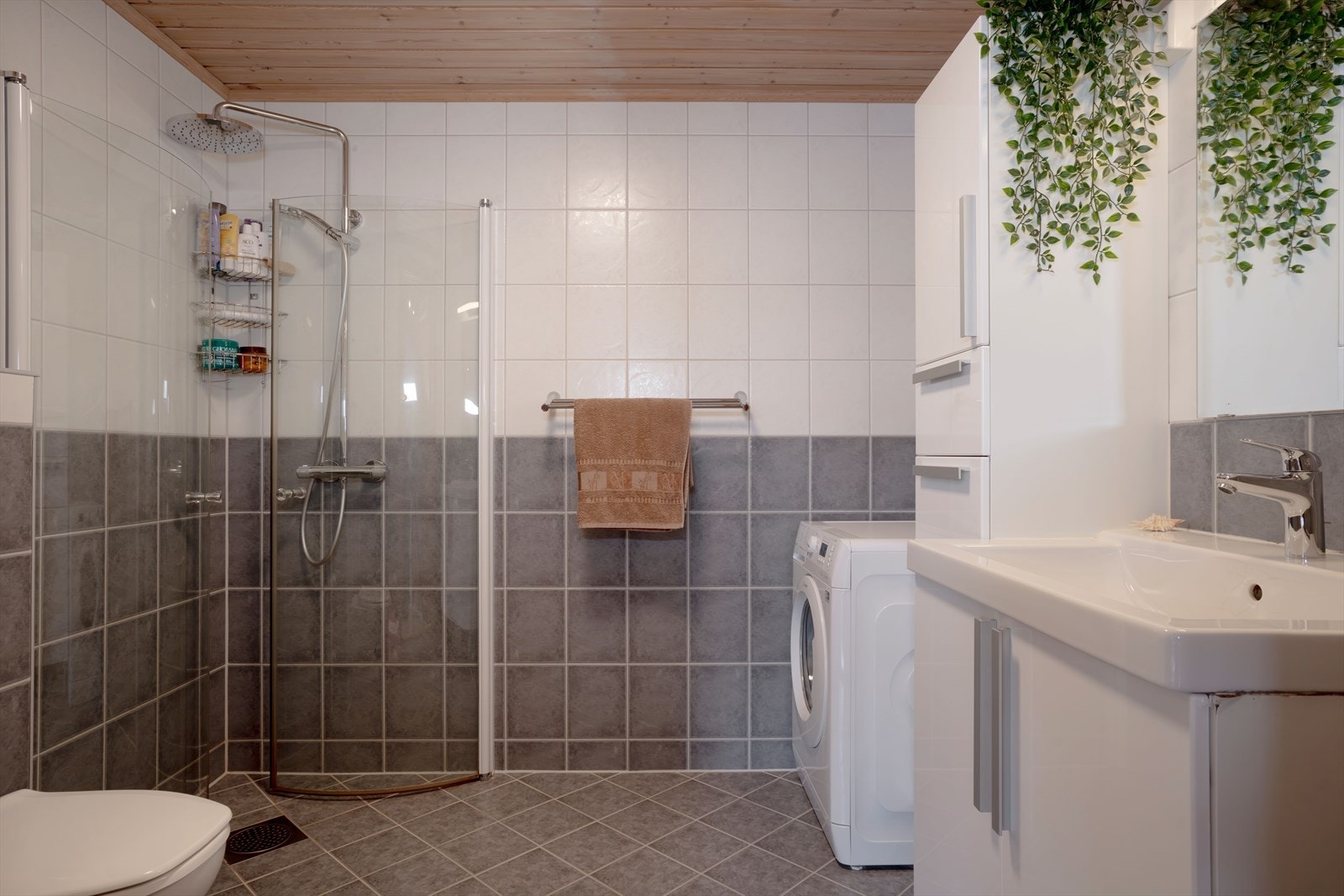 Badet i kjelleren er flislagt med varme i gulv og inneholder toalett, servant med innredning, dusjhjørne og opplegg til vaskemaskin. Galleribilde