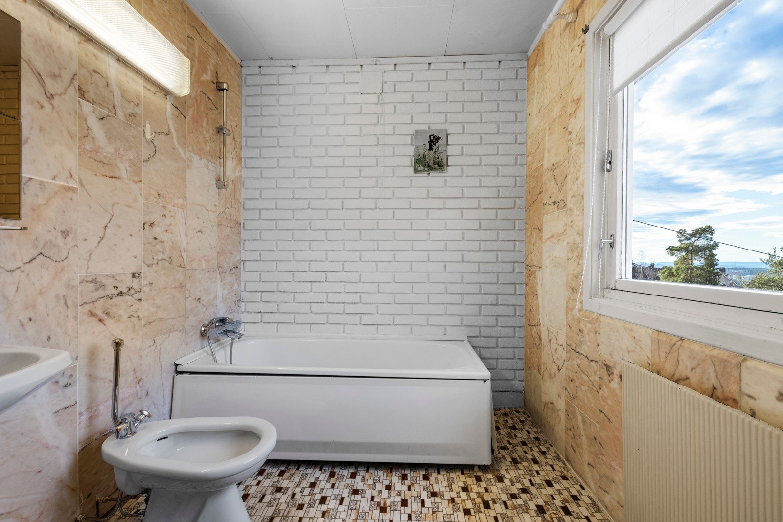 Badet er innredet med håndvask, speil, belysning, bidé, frittstående toalett og badekar med hånddusj Galleribilde