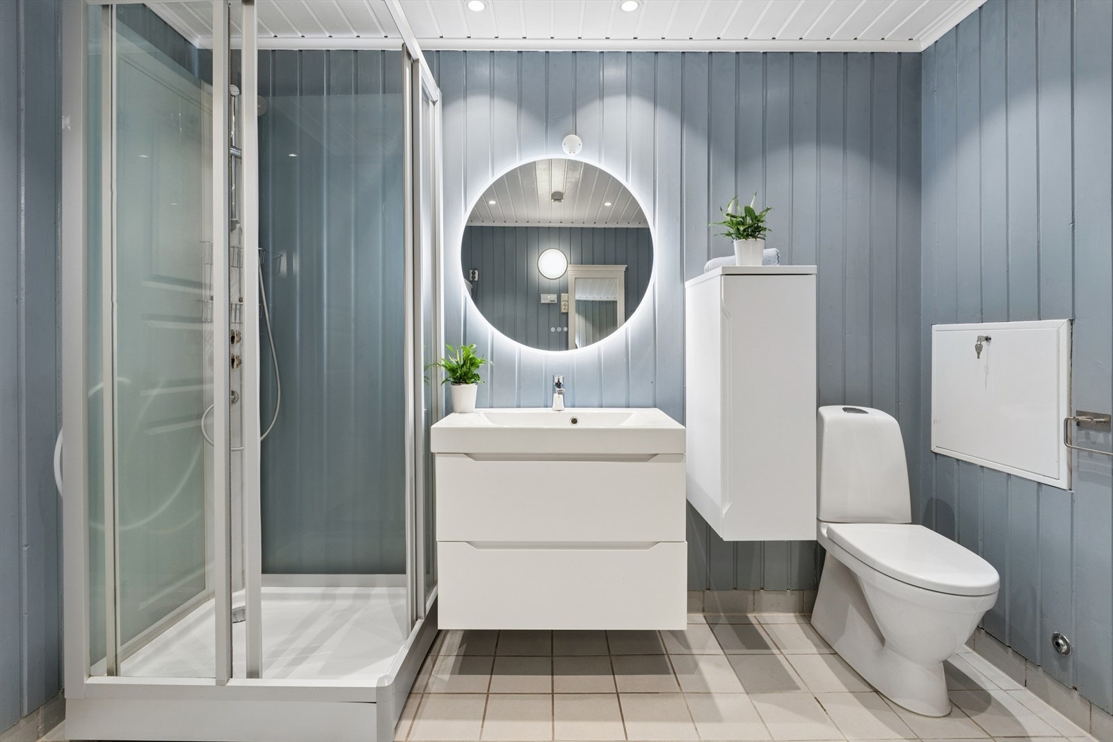 Badet er utstyrt med gulvstående toalett, dusjkabinett, samt baderomsinnredning med servant og speil. Galleribilde