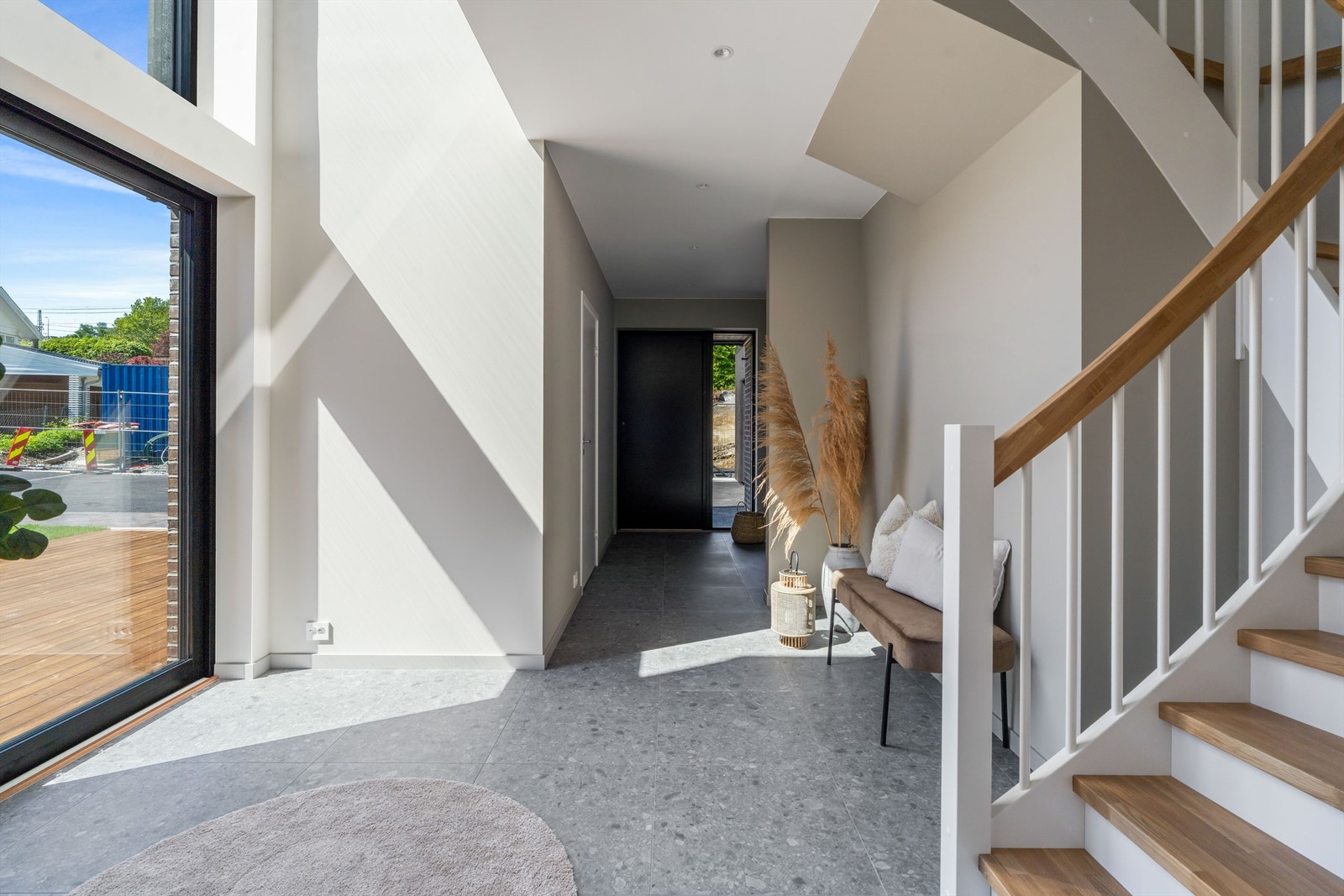 Gang / hall i 1 etg, mot inngangsdør. Gulvet er belagt med 60x60 fliser og det vannbåren varme i gulvene i huset.
Til høyre for inngangsdør ligger det bad med dusj, mens til høyre ligger vaskerommet. Der er det også utgang til gårdsrom og garasje. Galleribilde
