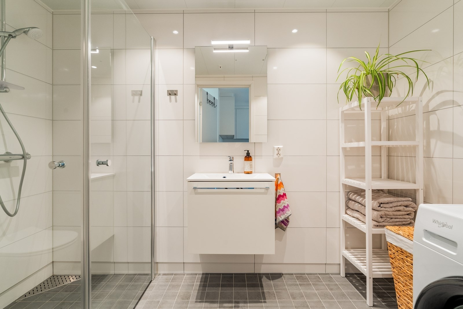 Badet er utstyrt med baderomsinnredning med nedfelt servant, vegghengt toalett dusj og opplegg for vaskemaskin Galleribilde