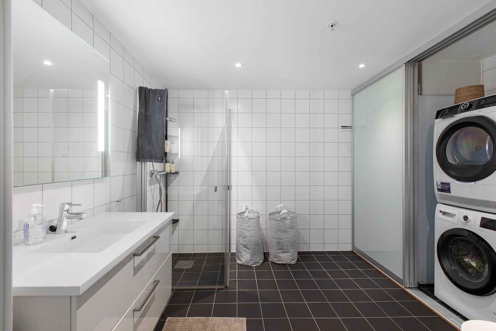 Badet har en praktisk nisje bak skyvedører med opplegg for vaskemaskin og tørketrommel. Galleribilde