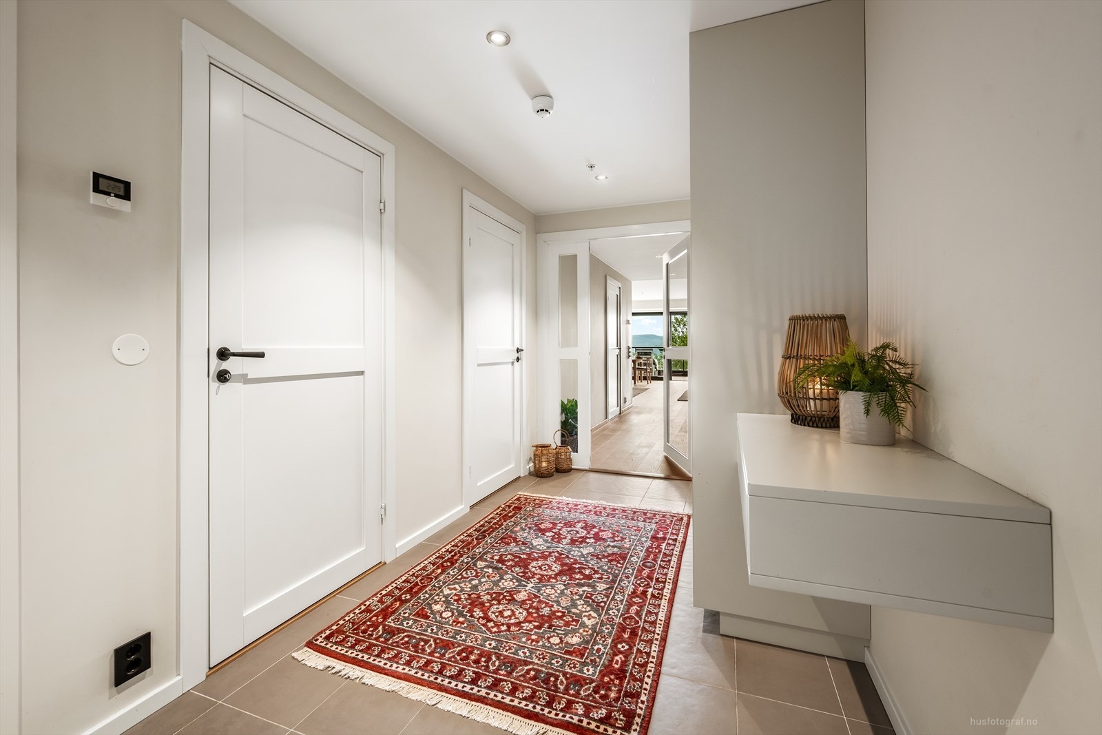 Fra gangen leder en glassdør inn til stuen, som skaper en åpen og lys overgang mellom rommene. Galleribilde
