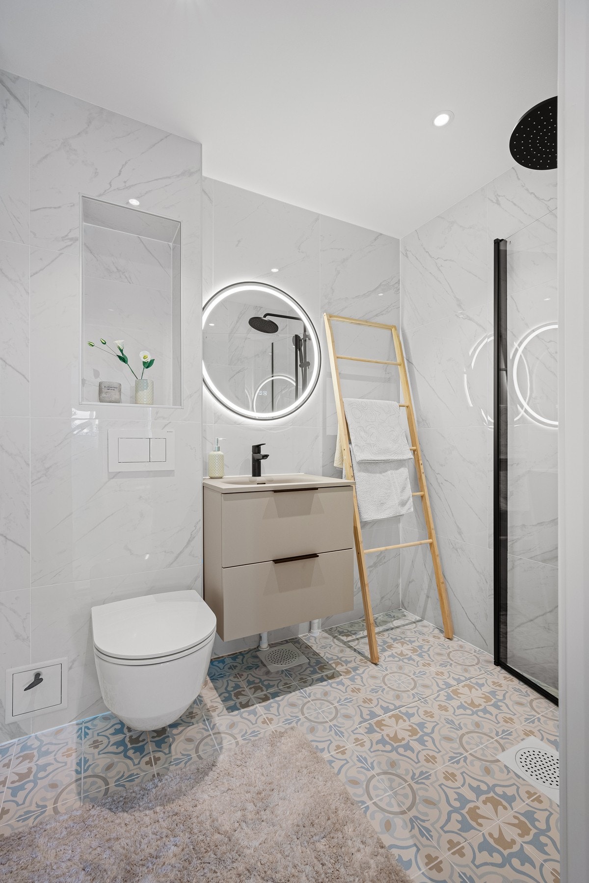Badet er innredet med dusjhjørne med glassdører, vegghengt toalett, lekker baderomsinnredning med nedsenket servant og speil med integrert belysning, samt opplegg for vaskemaskin. Galleribilde
