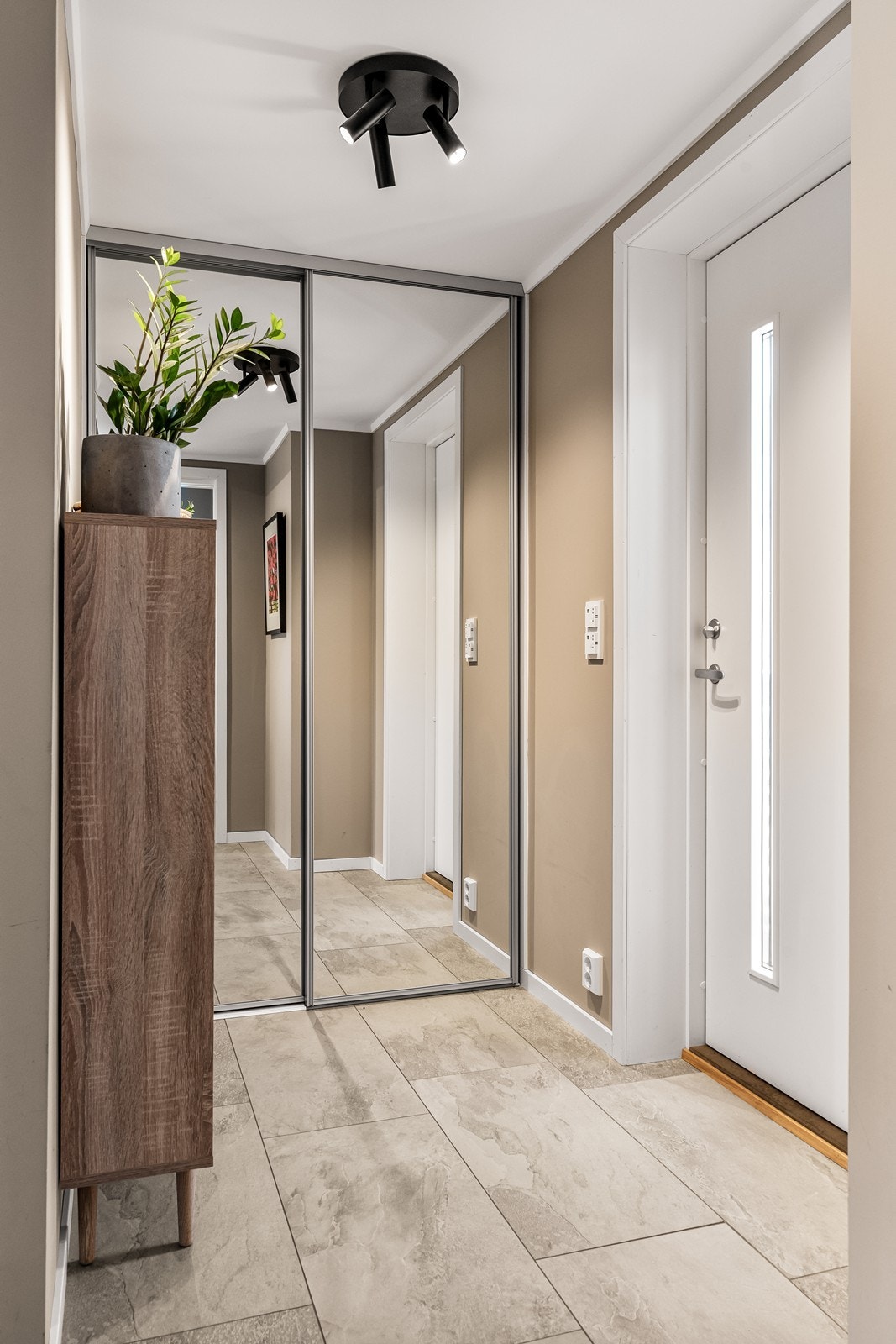 Skyvedørsgarderobe og flislagt gulv gir en funksjonell og oversiktlig entré. Galleribilde