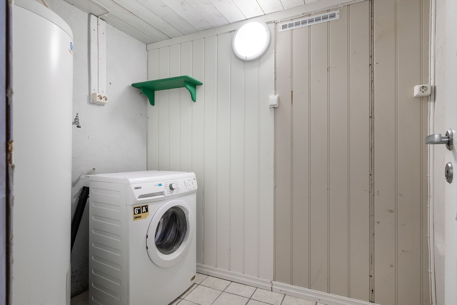 Praktisk vaskerom i kjelleren med flislagt gulv, opplegg for vaskemaskin. Galleribilde
