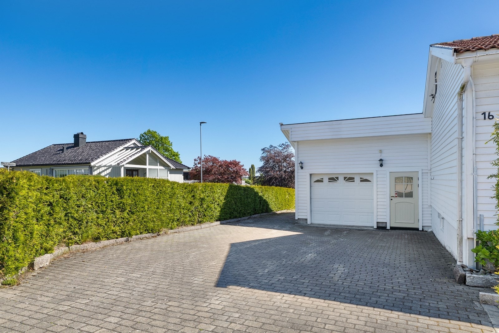 Integrert garasje og bod i tilbygg, med steinbelagt gårdsplass. Galleribilde