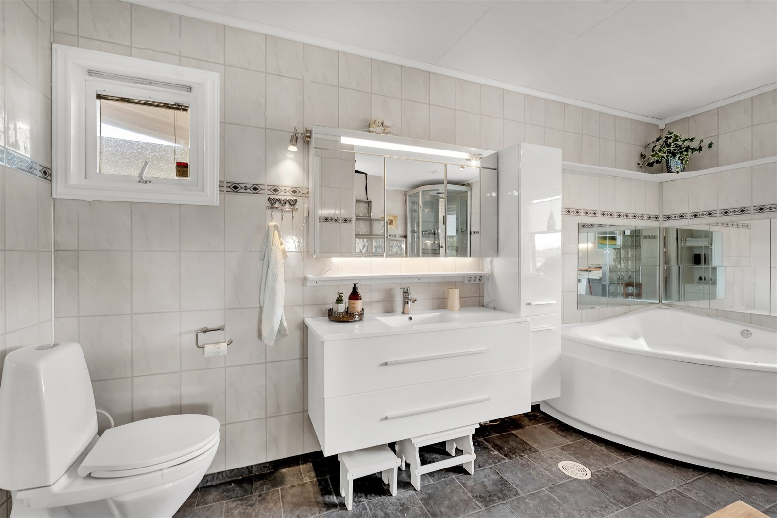 Innbydende bad/vaskerom med varme i gulv, samt rikelig med plass i innredning. Galleribilde