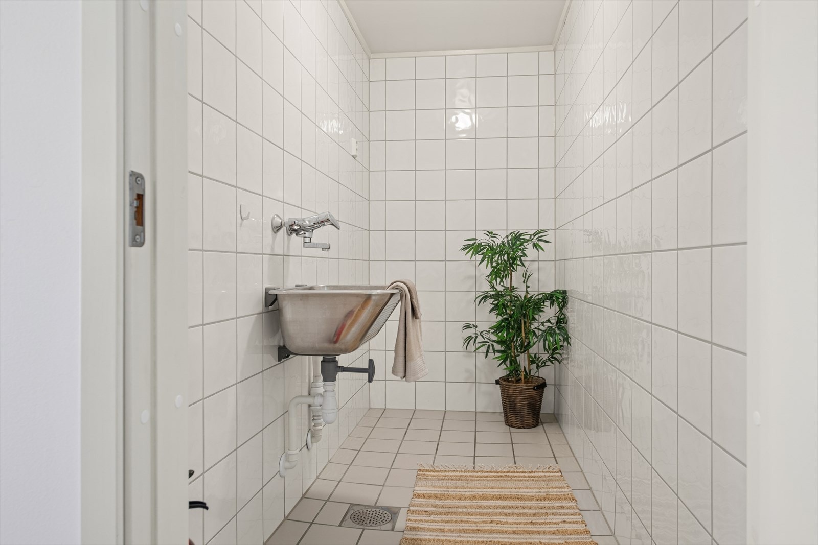 Praktisk, separat vaskerom med fliser på gulv og vegger, gulvvarme og opplegg for vaskemaskin. Galleribilde