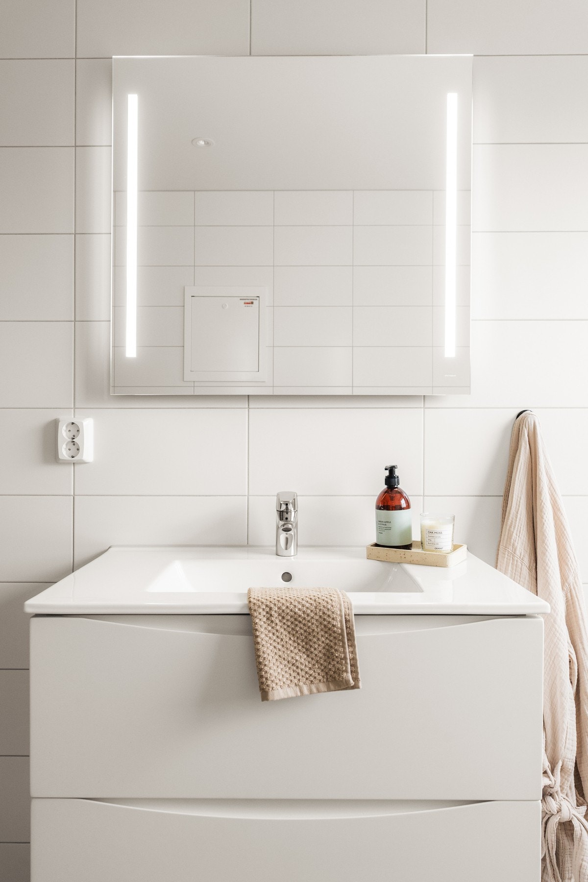 Badet har en tidløs innredning med dusj med glassvegg, vegghengt toalett og baderomsinnredning med speil og belysning. Opplegg for vaskemaskin og muligheter for å sette inn badekar. Galleribilde