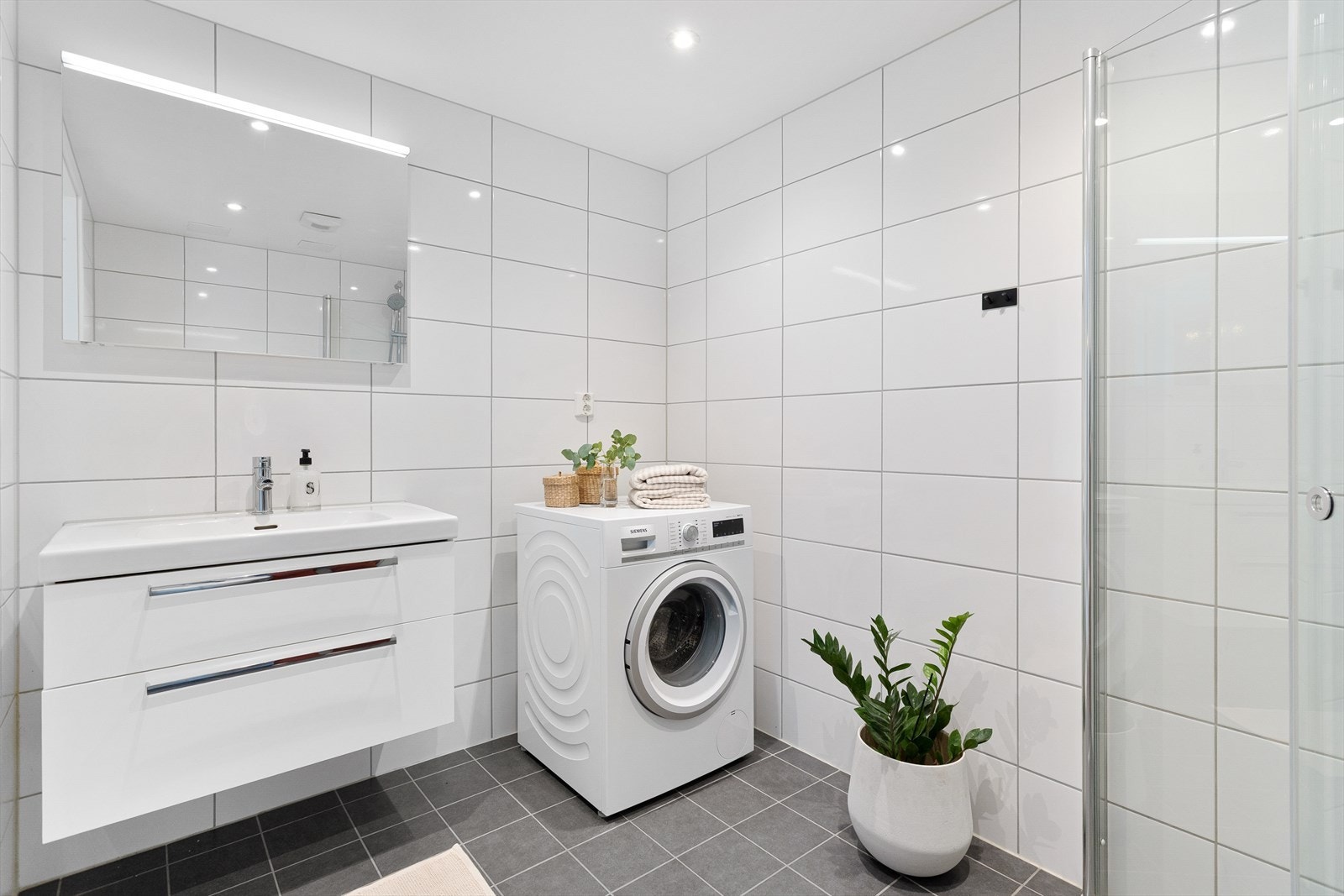 Lyst og delikat flislagt bad med elektriske varmekabler og downlights i taket. Galleribilde