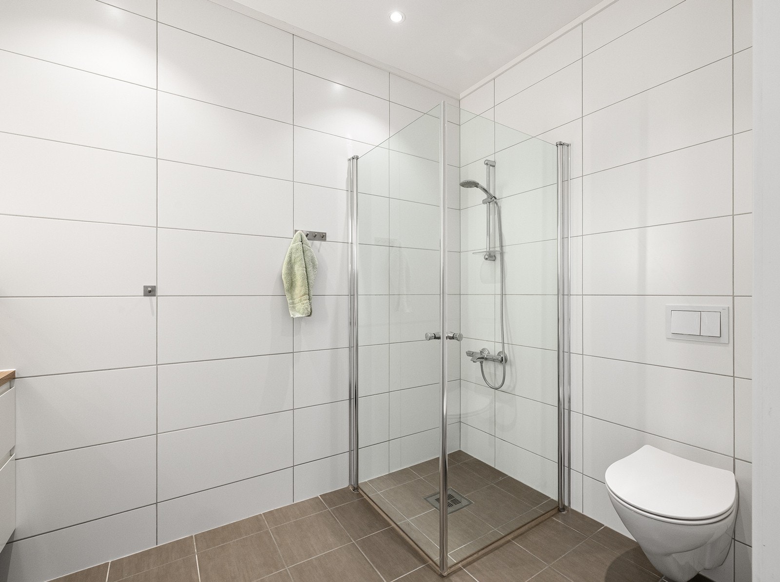 Badet har oppgraderte detaljer som matte, hvite veggfliser og mørkere gulvfliser med matchende mosaikk i den nedsenkede dusjsonen, fullført med en moderne Stratos slukrist. Galleribilde