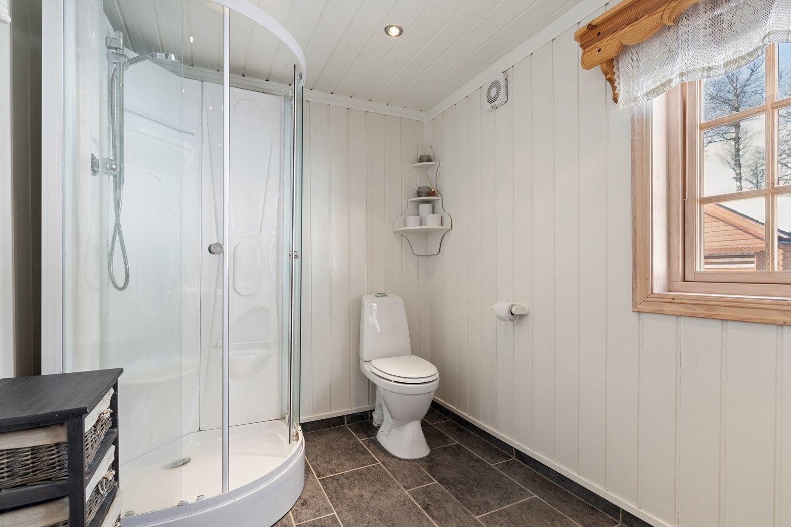 Badet er utstyrt med dusjkabinett, gulvmontert toalett og avtrekksvifte. Galleribilde