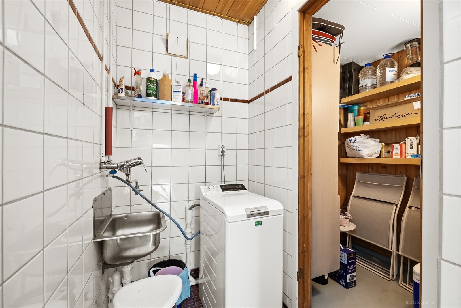 Praktisk vaskerom i kjelleren med flislagte overflater, skyllekar og opplegg for vaskemaskin. Galleribilde