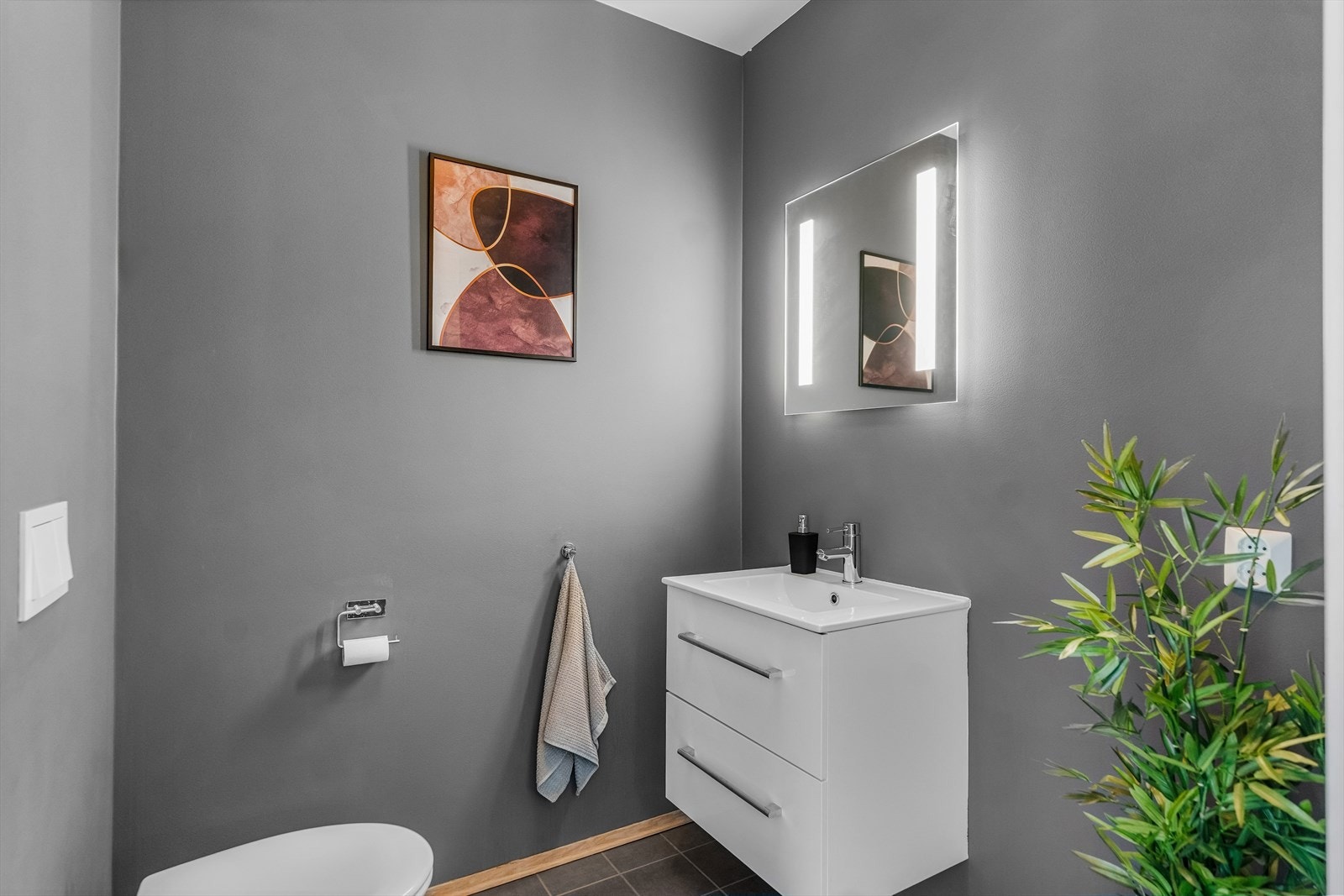 Fra stuen er det inngang til et praktisk toalettrom. Rommet er utstyrt med toalett, servant med underskuffer og speil. Galleribilde