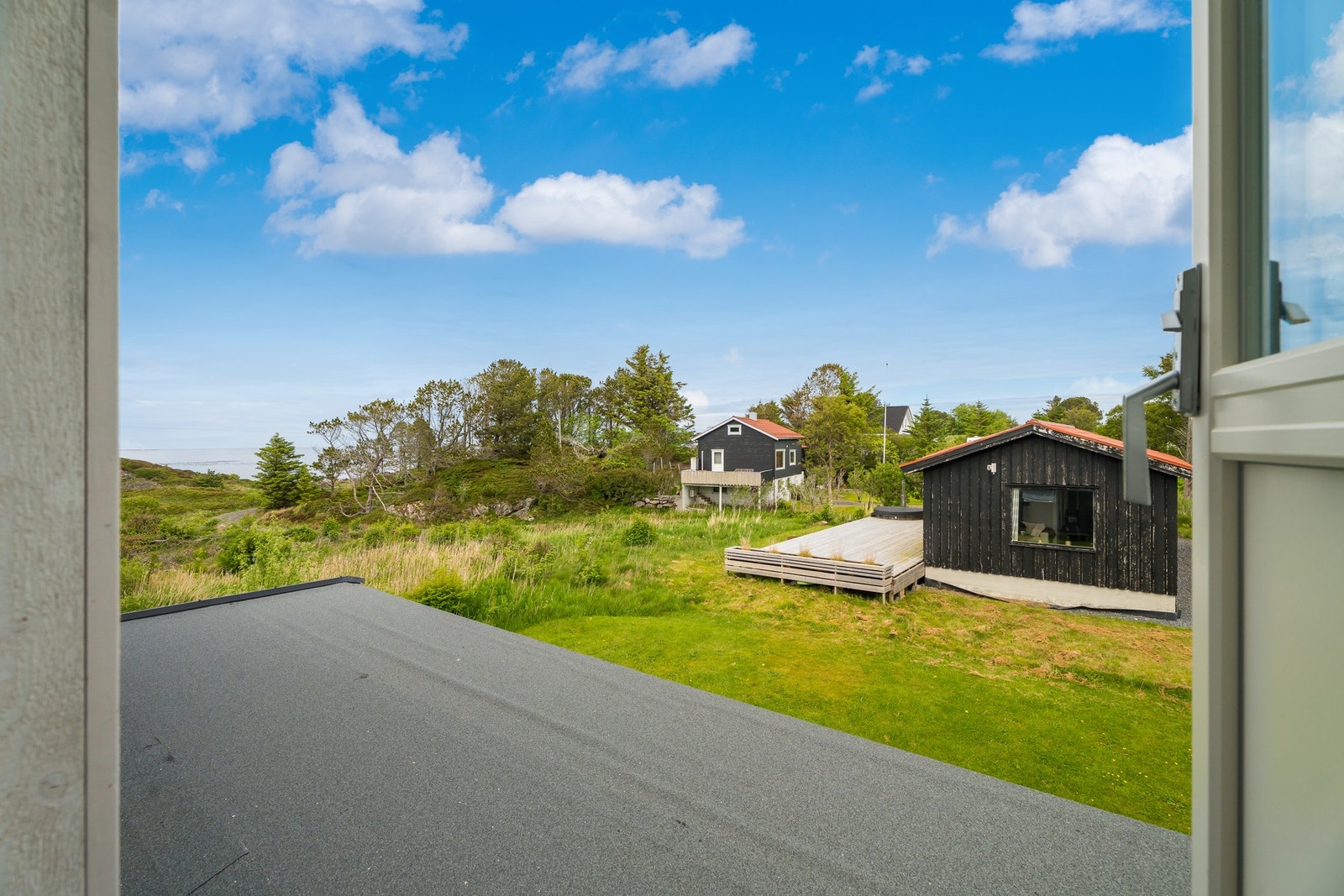 Vi tar en titt ut av verandadøren Til venstre på bildet skimter du vegen ned til den idylliske området ved sjøen. Galleribilde