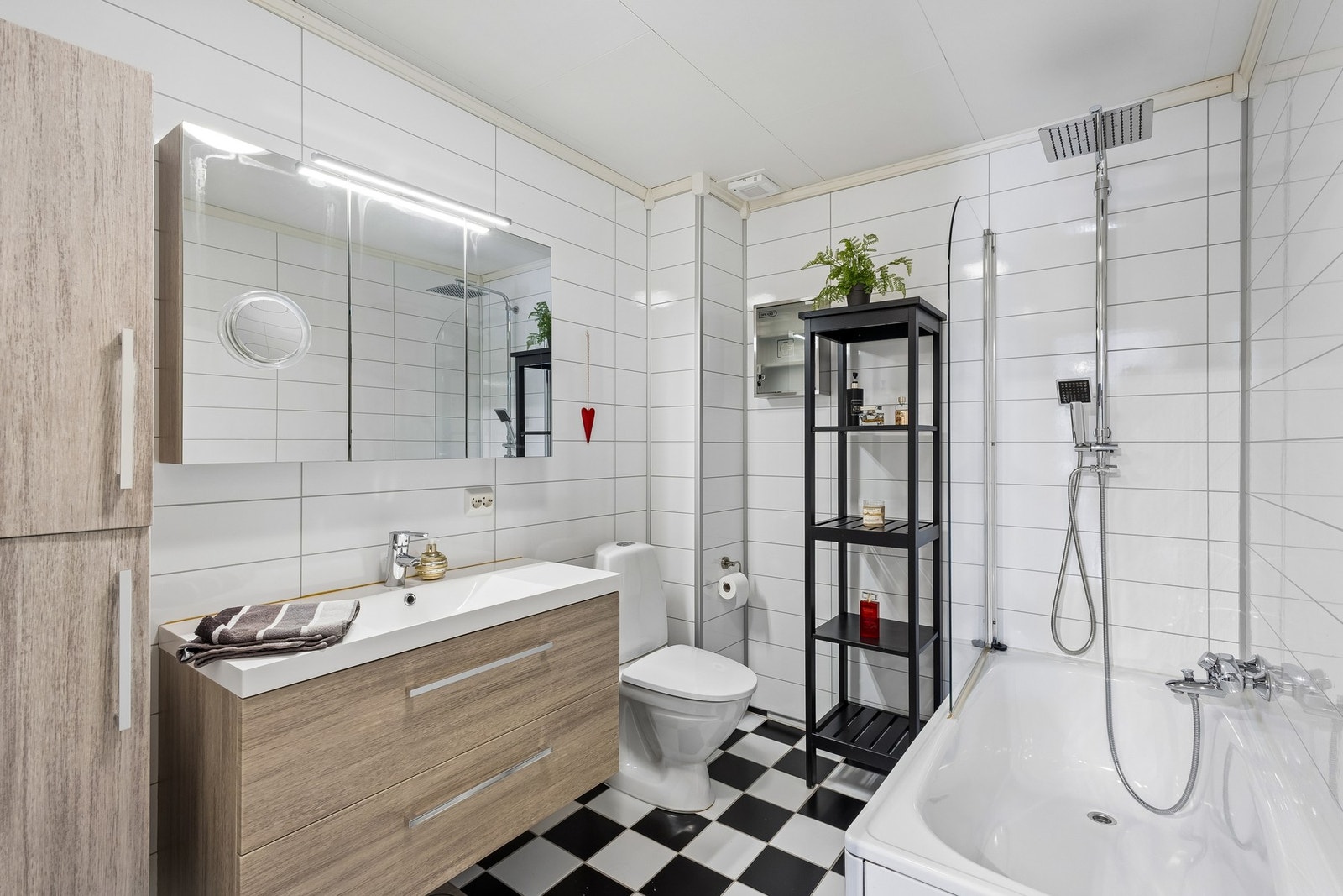 Badet har flislagt gulv og baderomsplater på veggene. Innredningen består av servantseksjon med underskuffer, høyskap for ekstra oppbevaring samt badekar med dusjløsning. Galleribilde