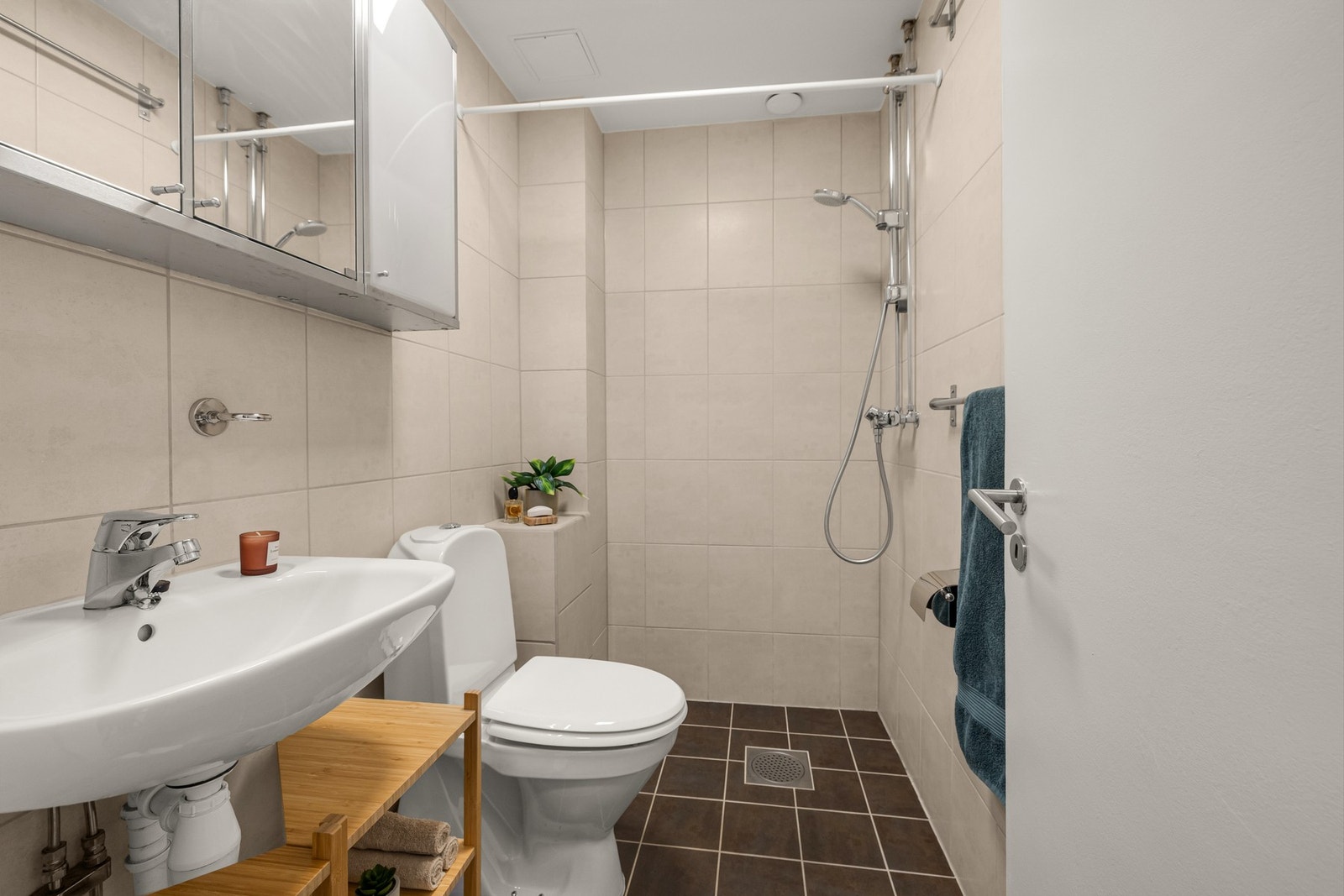 Badet er flislagt og funksjonelt innredet med gulvvarme, vegghengt servant med speilskap og dusjløsning Galleribilde